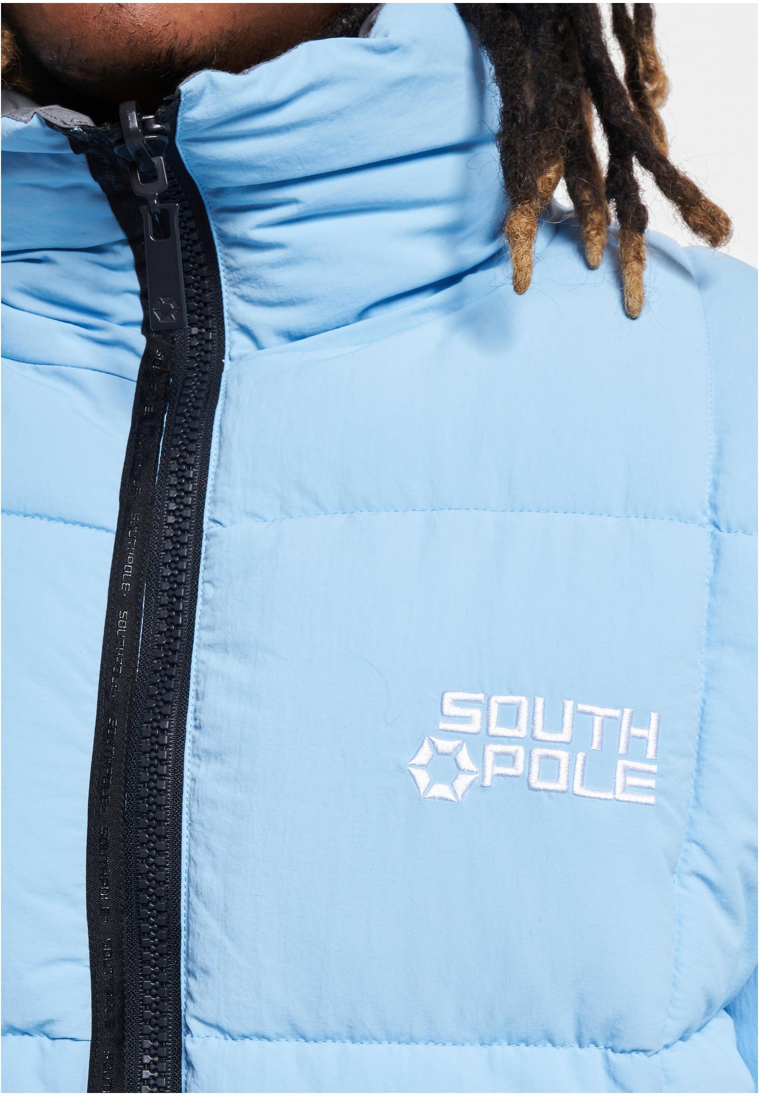 Närbild på en ljusblå Southpole pufferjacka med fokus på den broderade logotypen och den svarta dragkedjan.