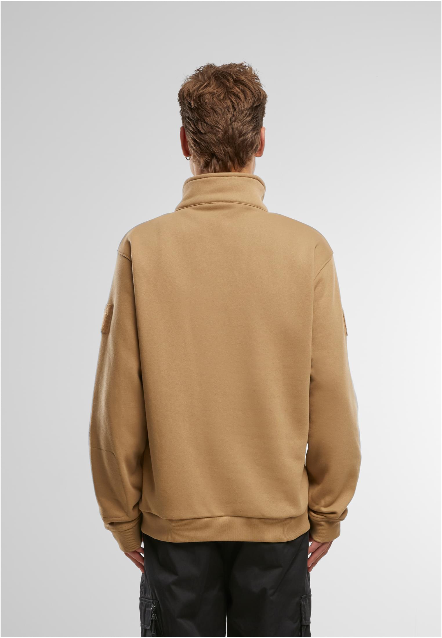 En man visar baksidan av en beige B Tactical Sweat Troyer.