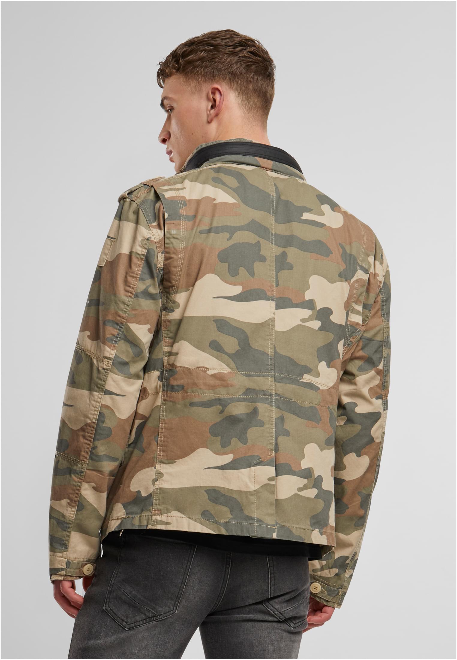 En man visar baksidan av B Britannia Jacket i kamouflage.