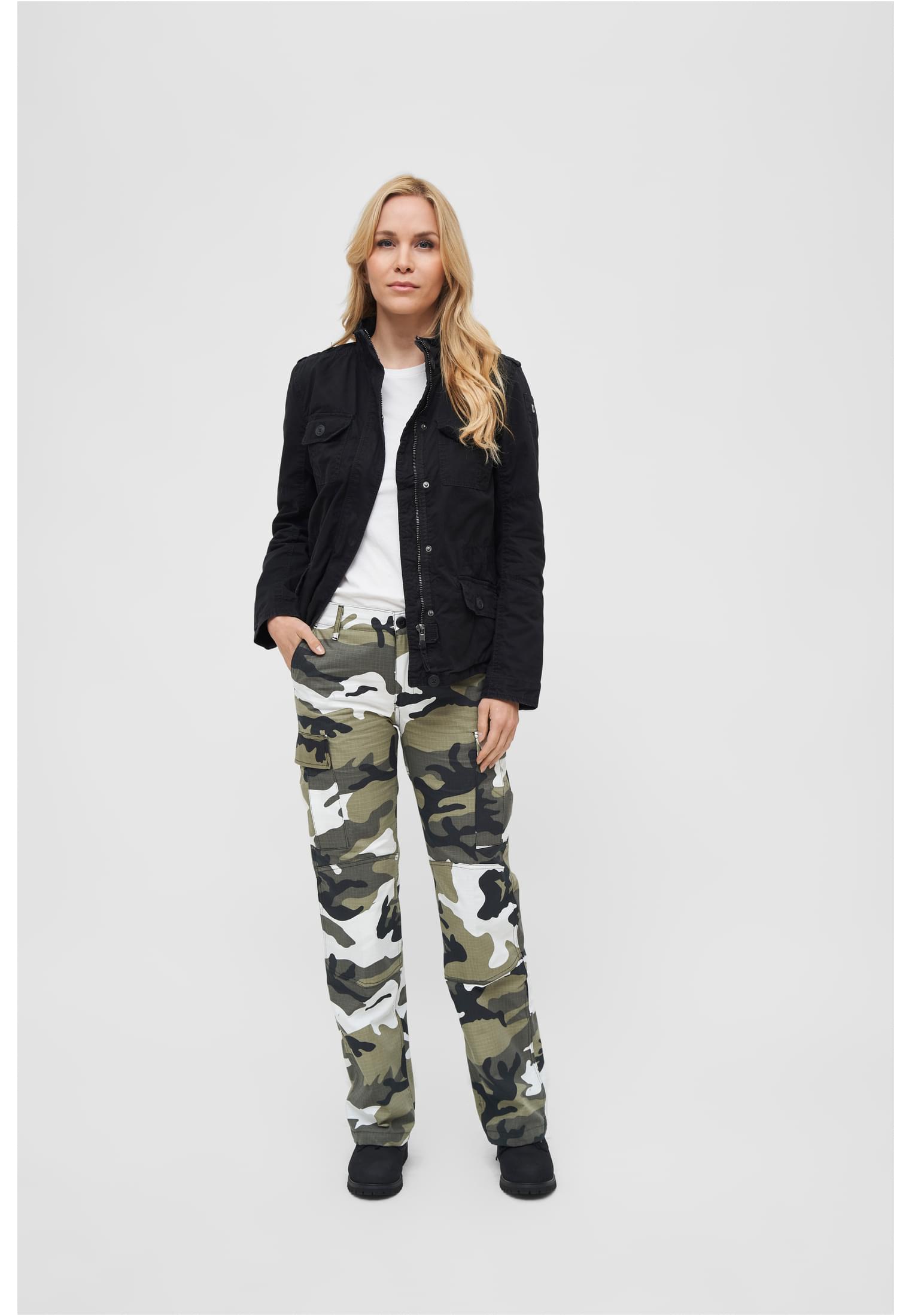En kvinna visar framsidan av den svarta B Britannia Jacket, stylad med en vit t-shirt och kamouflagebyxor.