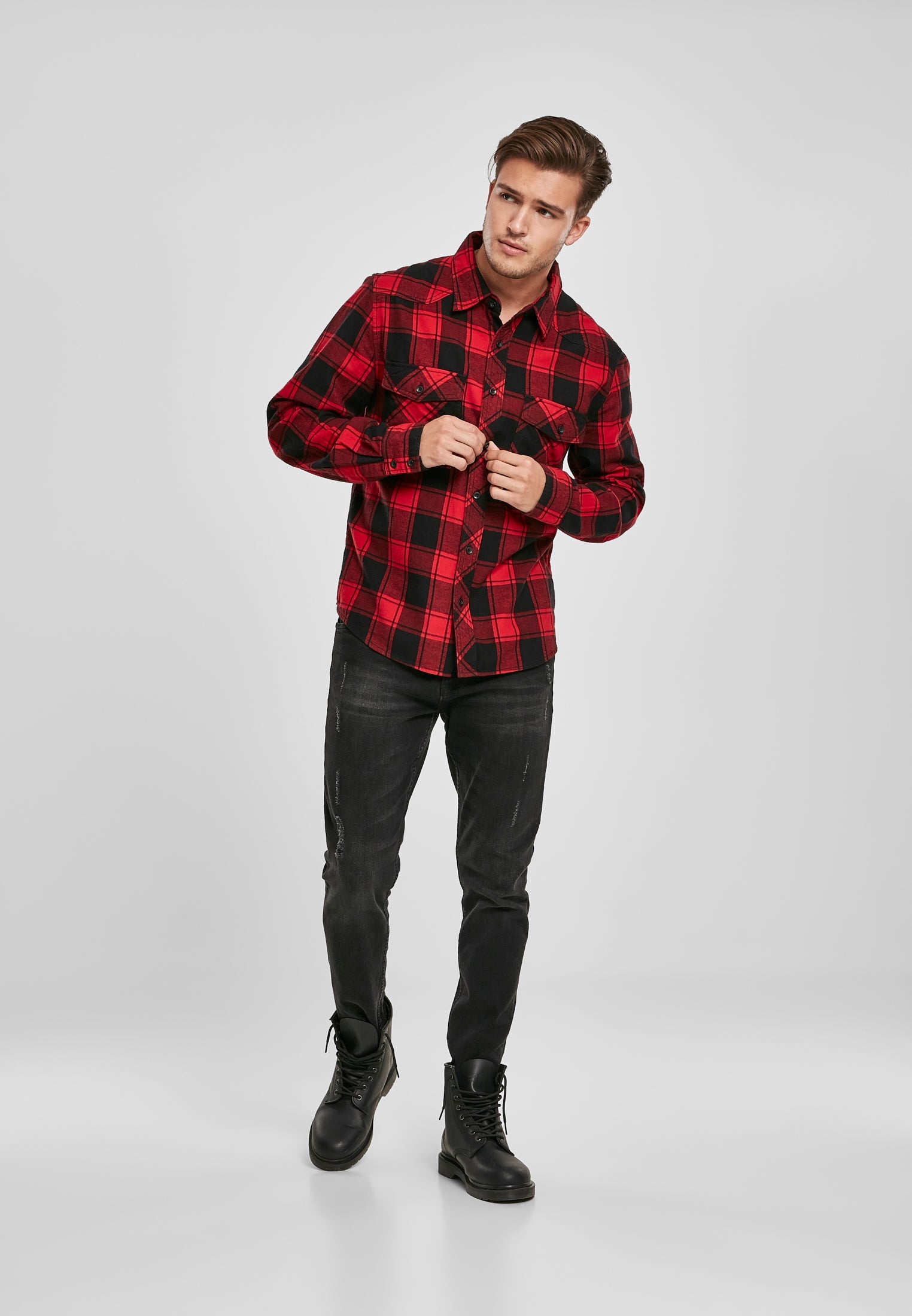 Helbild på en man som bär den röda och svarta rutiga B Checkshirt med svarta jeans och kängor.