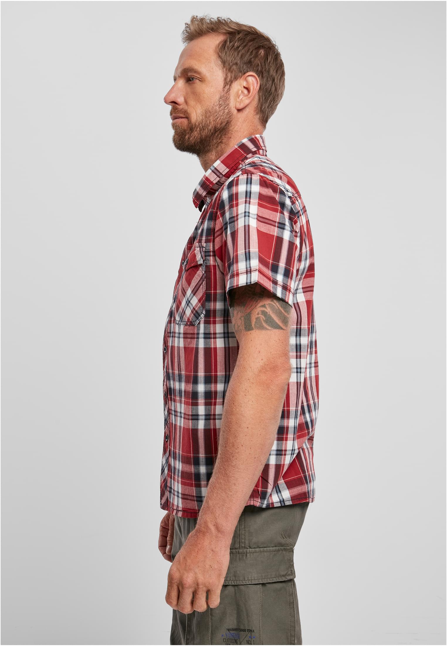 En man visar sidan av sin kortärmade, rödrutiga B Roadstar-skjorta.