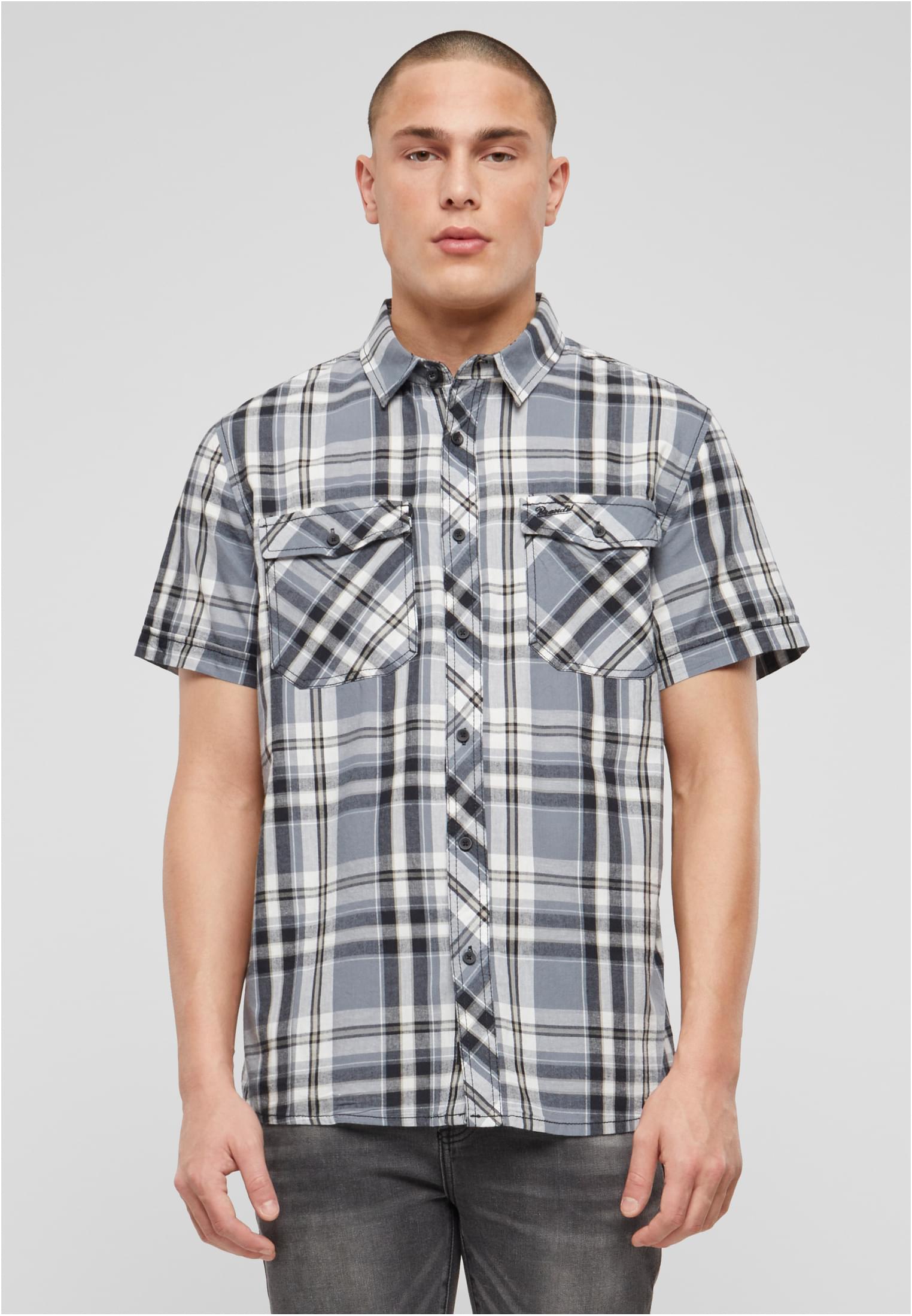 En man visar framsidan av en kortärmad, rutig skjorta i grått, svart och vitt.