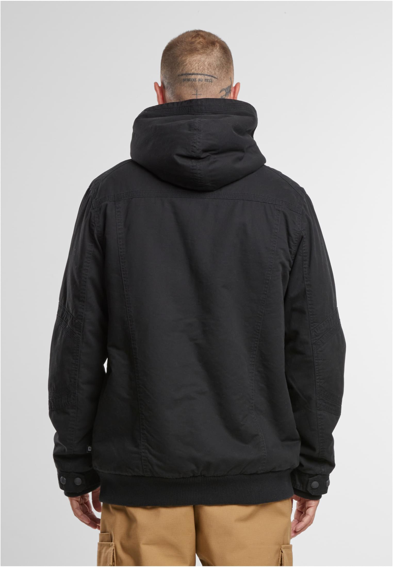 En man visar baksidan av en svart B Meadow Jacket från Brandit.