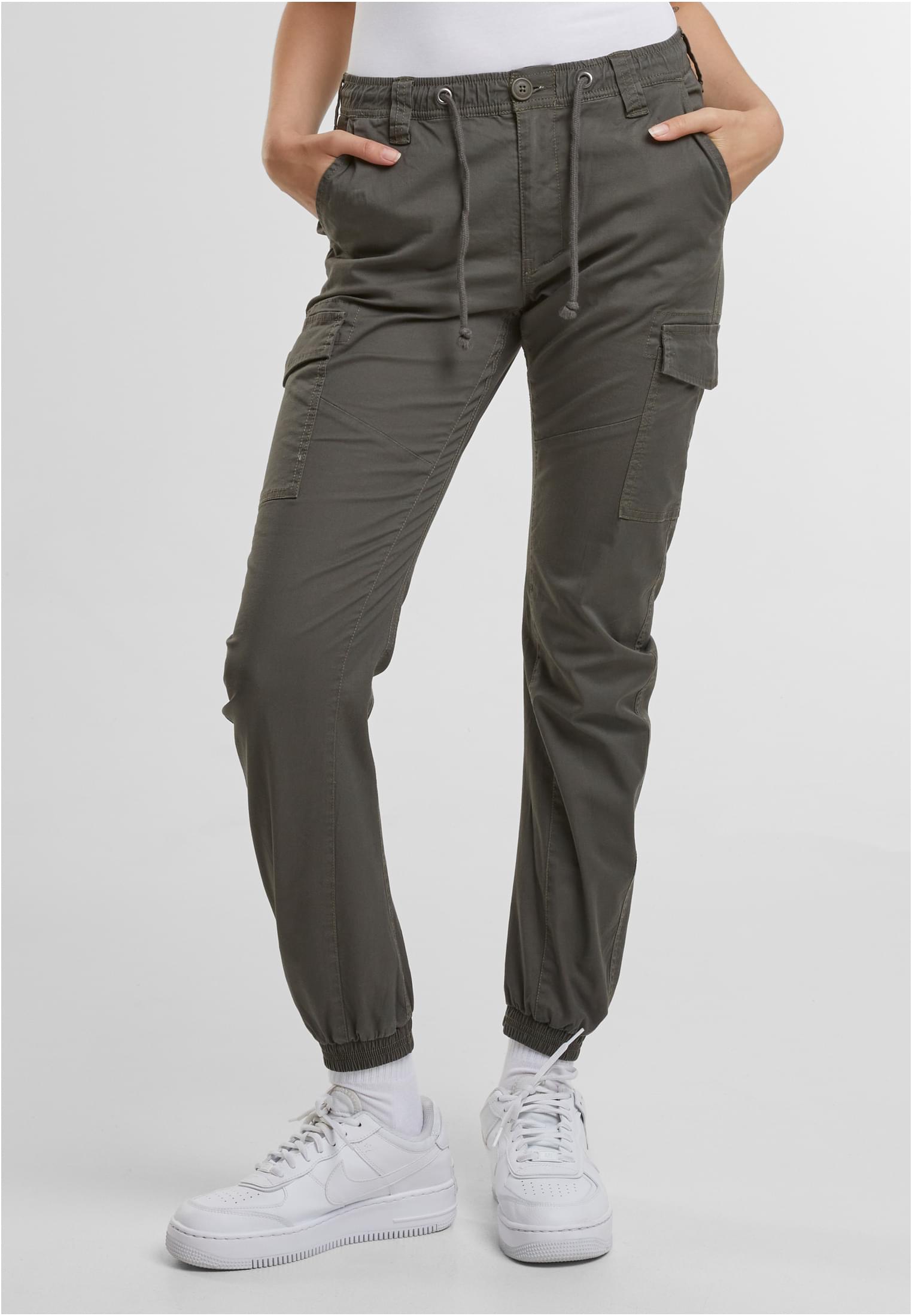 En kvinna bär olivgröna Brandit Melina cargobyxor och har händerna i fickorna.