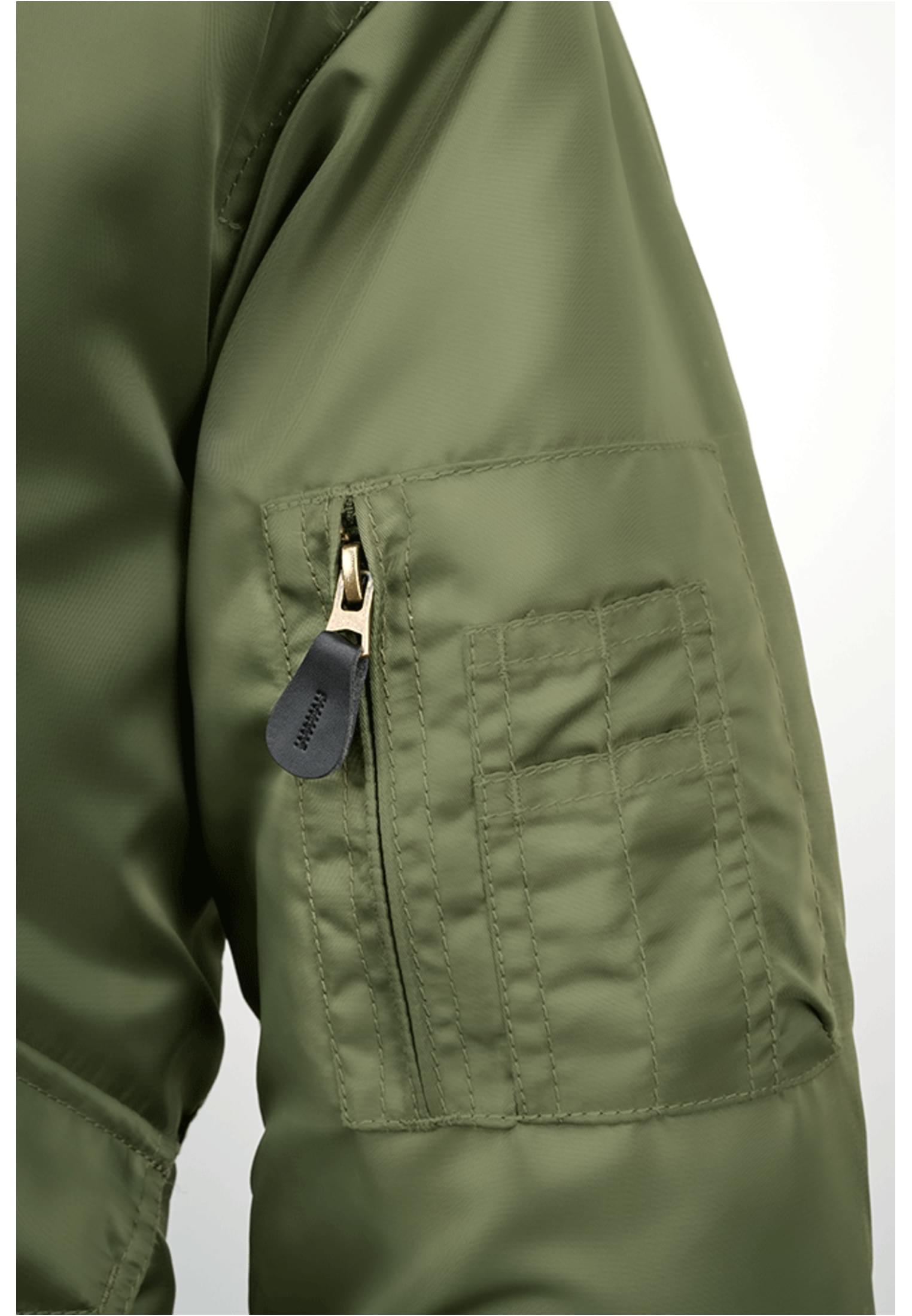 Närbild på ärmfickan med dragkedja på en olivgrön B CWU-jacka.