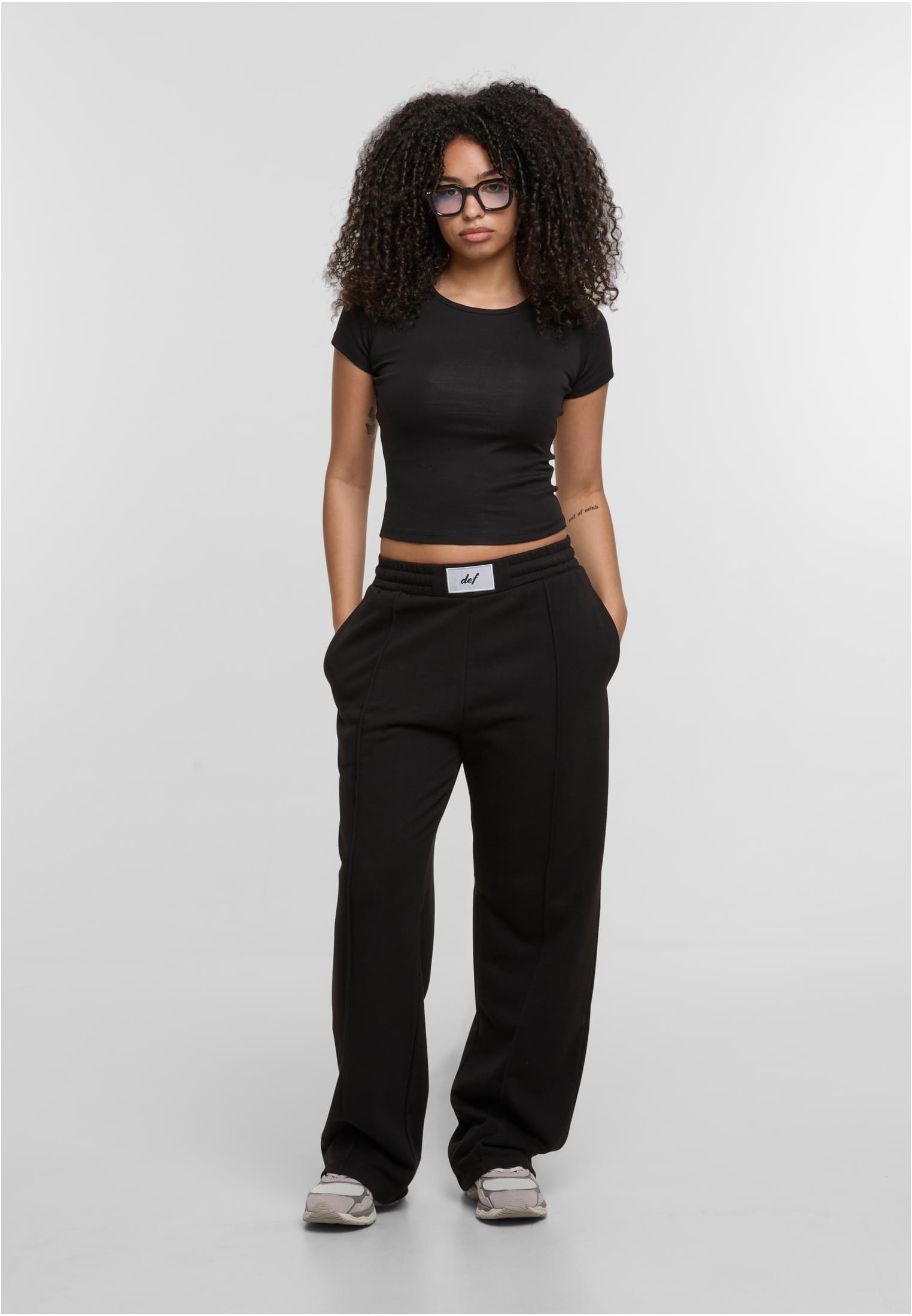 En kvinna som bär en svart DEF Relax T-shirt och svarta byxor.