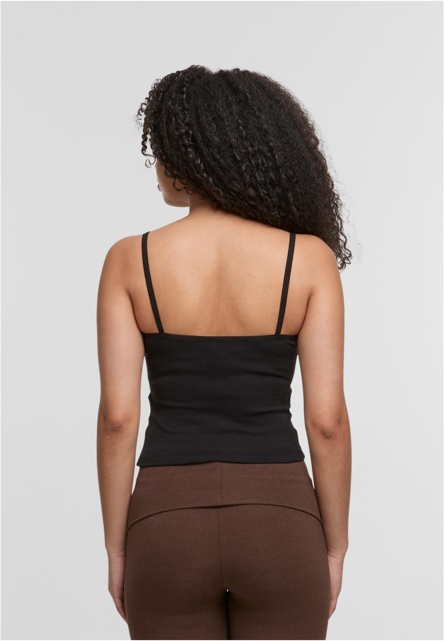 En kvinna visar baksidan av ett svart ribbat linne med smala axelband.