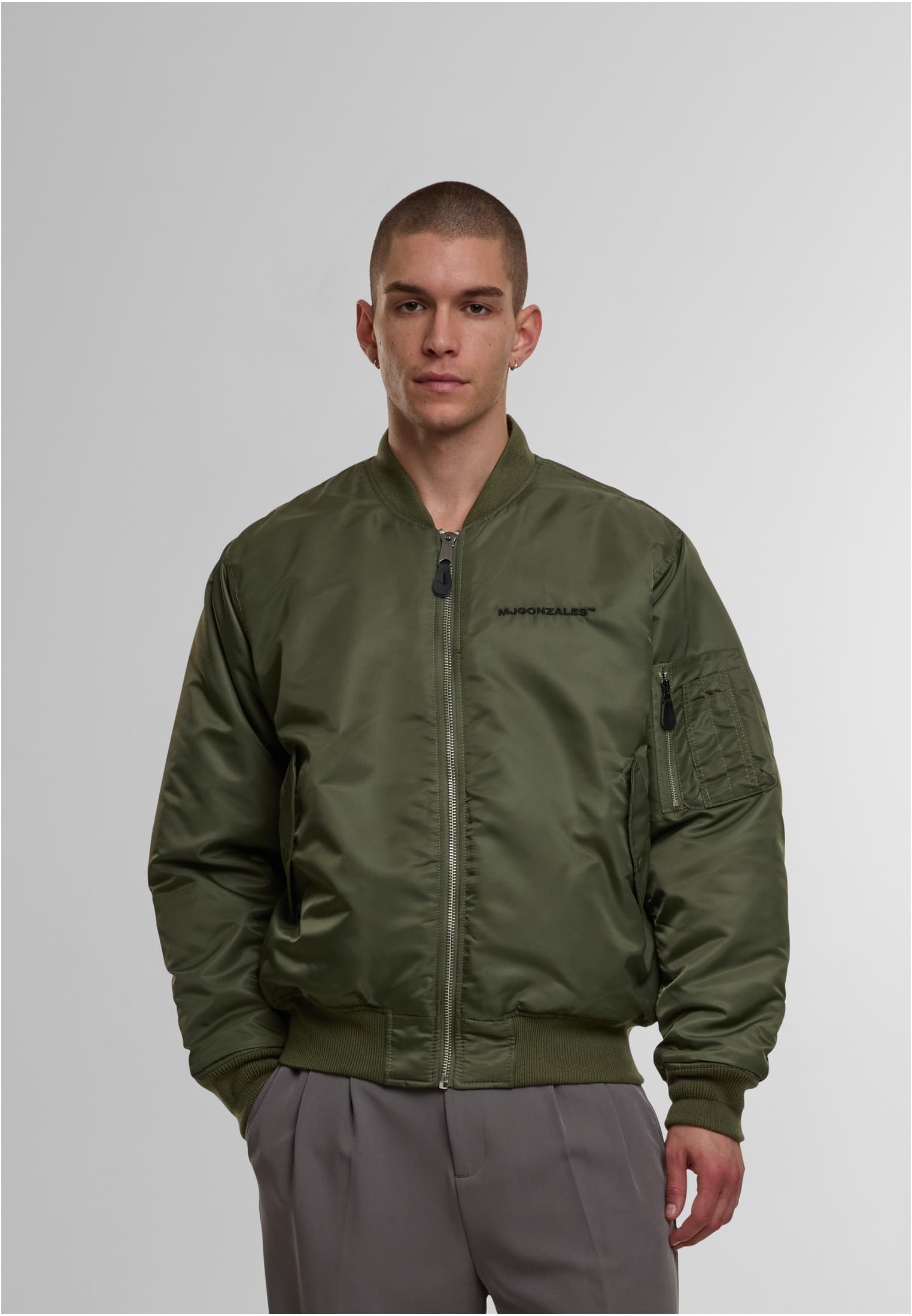 En manlig modell bär en olivgrön MJG Bomber Jacket och tittar in i kameran.