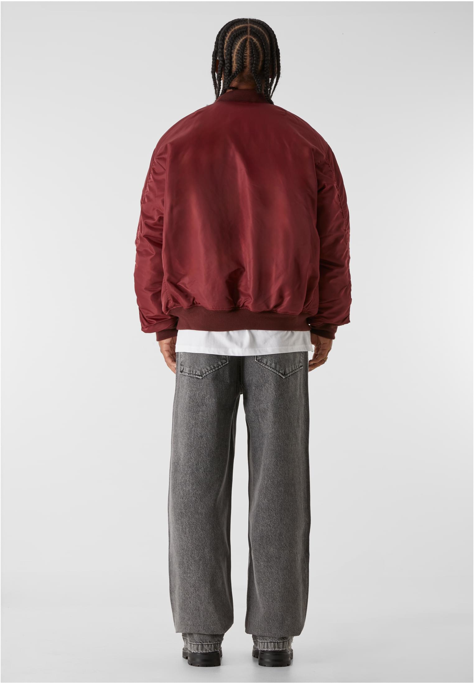 En man visar baksidan av en vinröd MJG Bomberjacka.