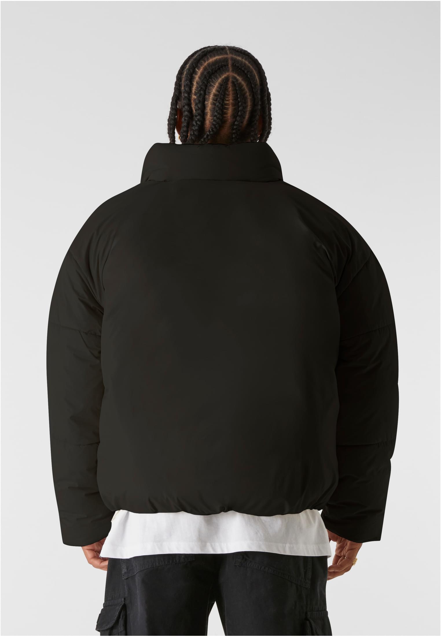 Baksidan av en man som bär en svart MJG Puffer Jacket.