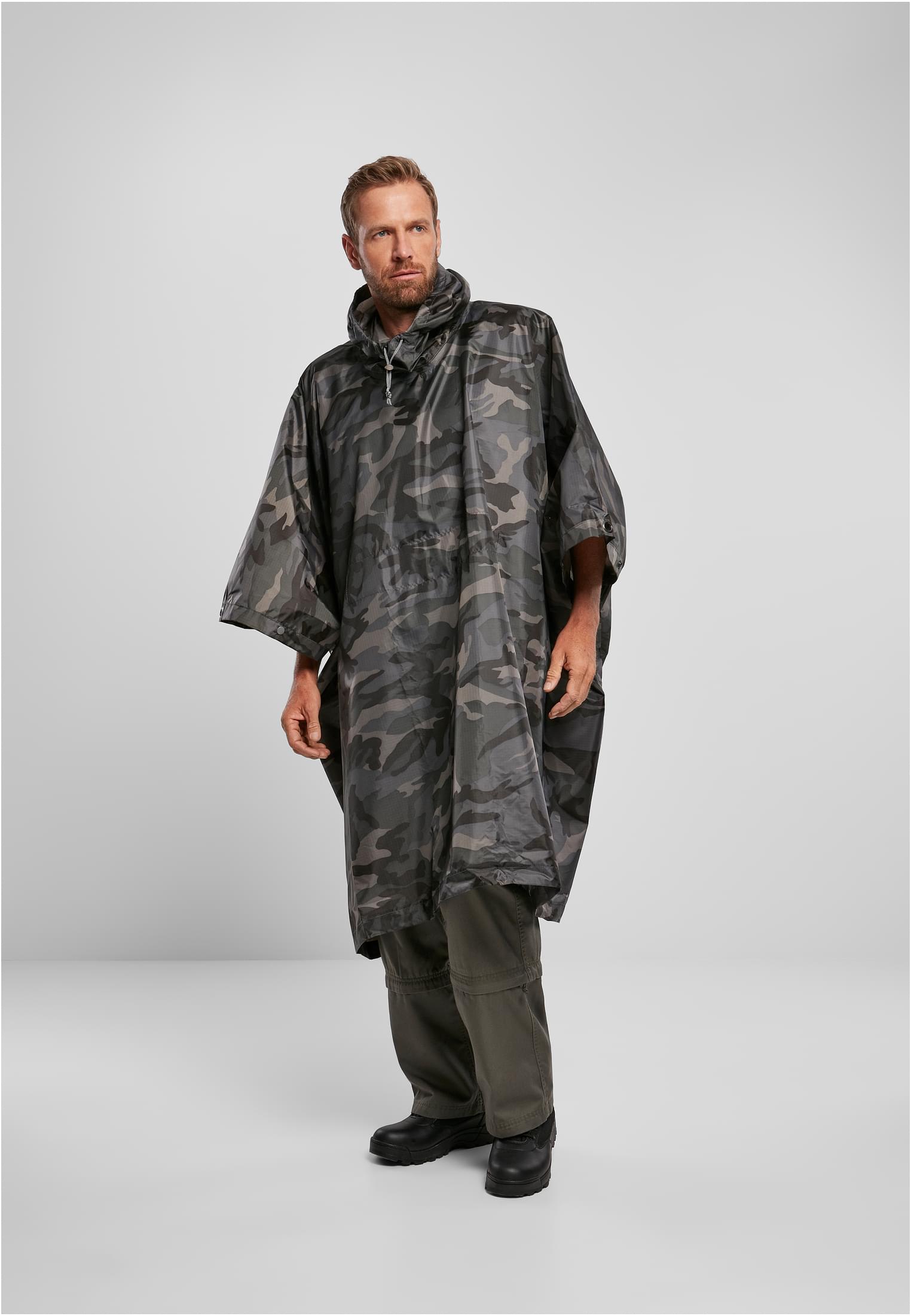 En man poserar i en B Ripstop Poncho i taktiskt kamouflage.