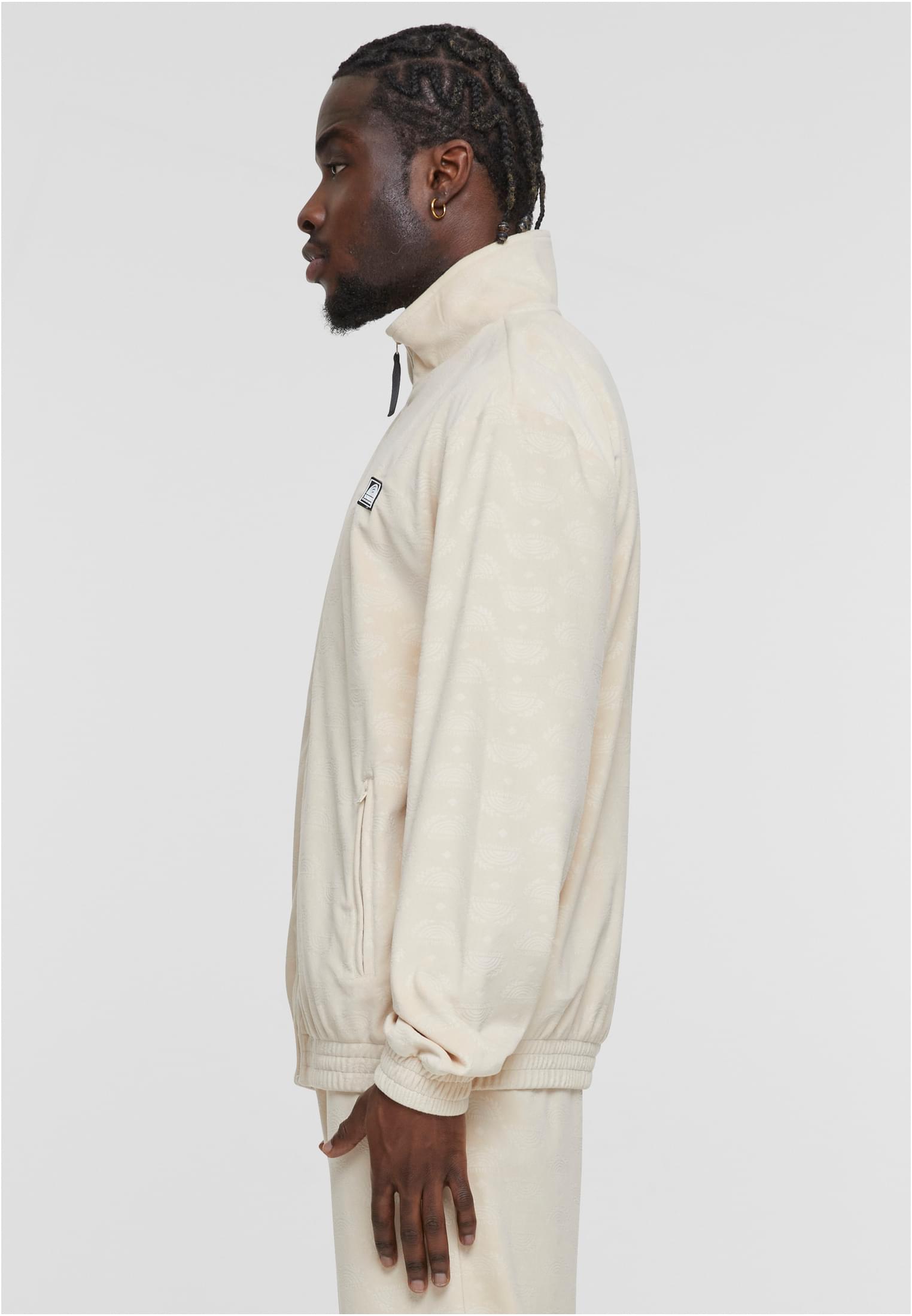 En man i profil som bär en beige velourjacka med heltäckande mönster.