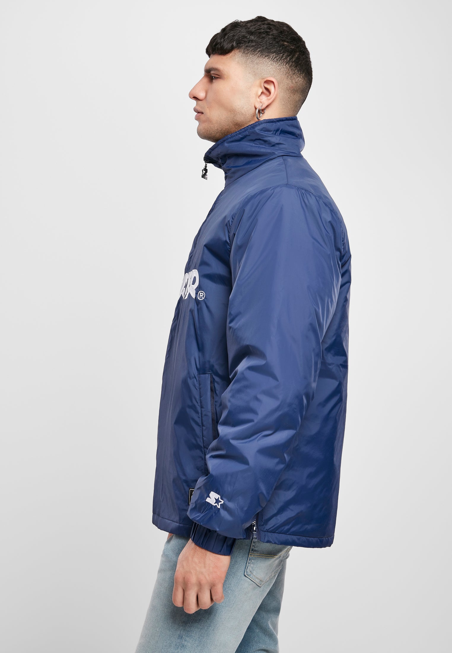 Sidovy av en man som bär den blå SBL Starter Logo Half Zip Jackan.