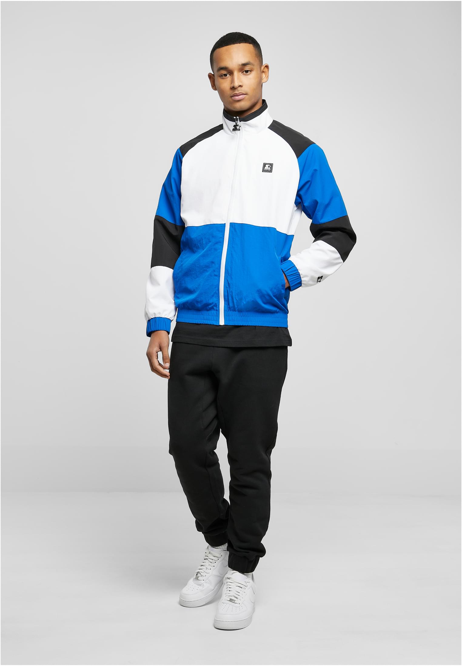En manlig modell visar framsidan av en SBL Starter Color Block Retro Jacket med blått, vitt och svart färgblocksmönster.