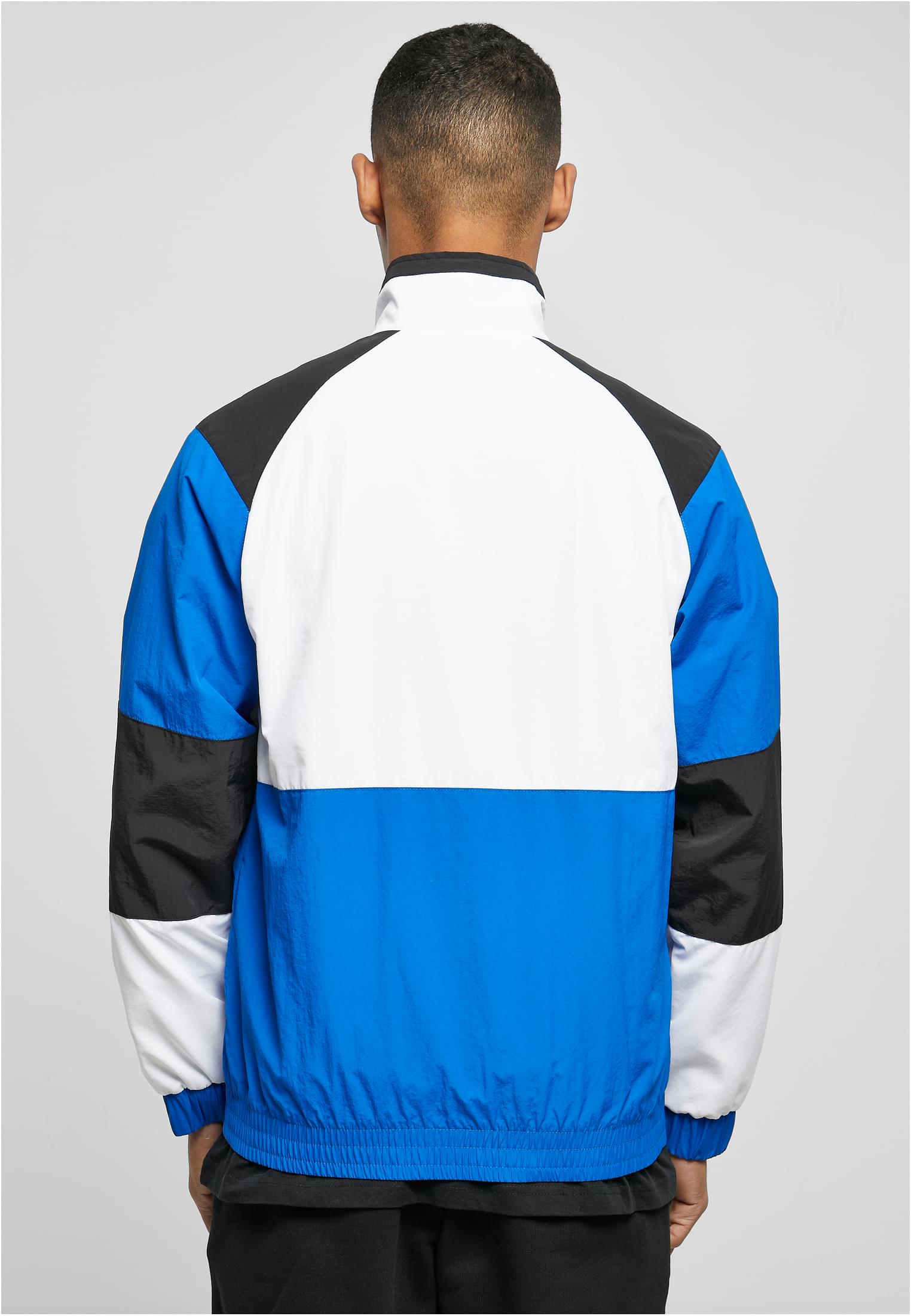 Baksidan av en man som bär en retrojacka med färgblock i blått, vitt och svart.