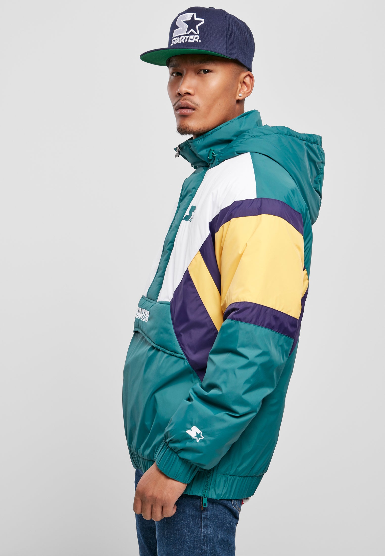 En man i sidoprofil som bär en SBL Starter Color Block Half Zip Retro Jacka i grönt, vitt, gult och lila.