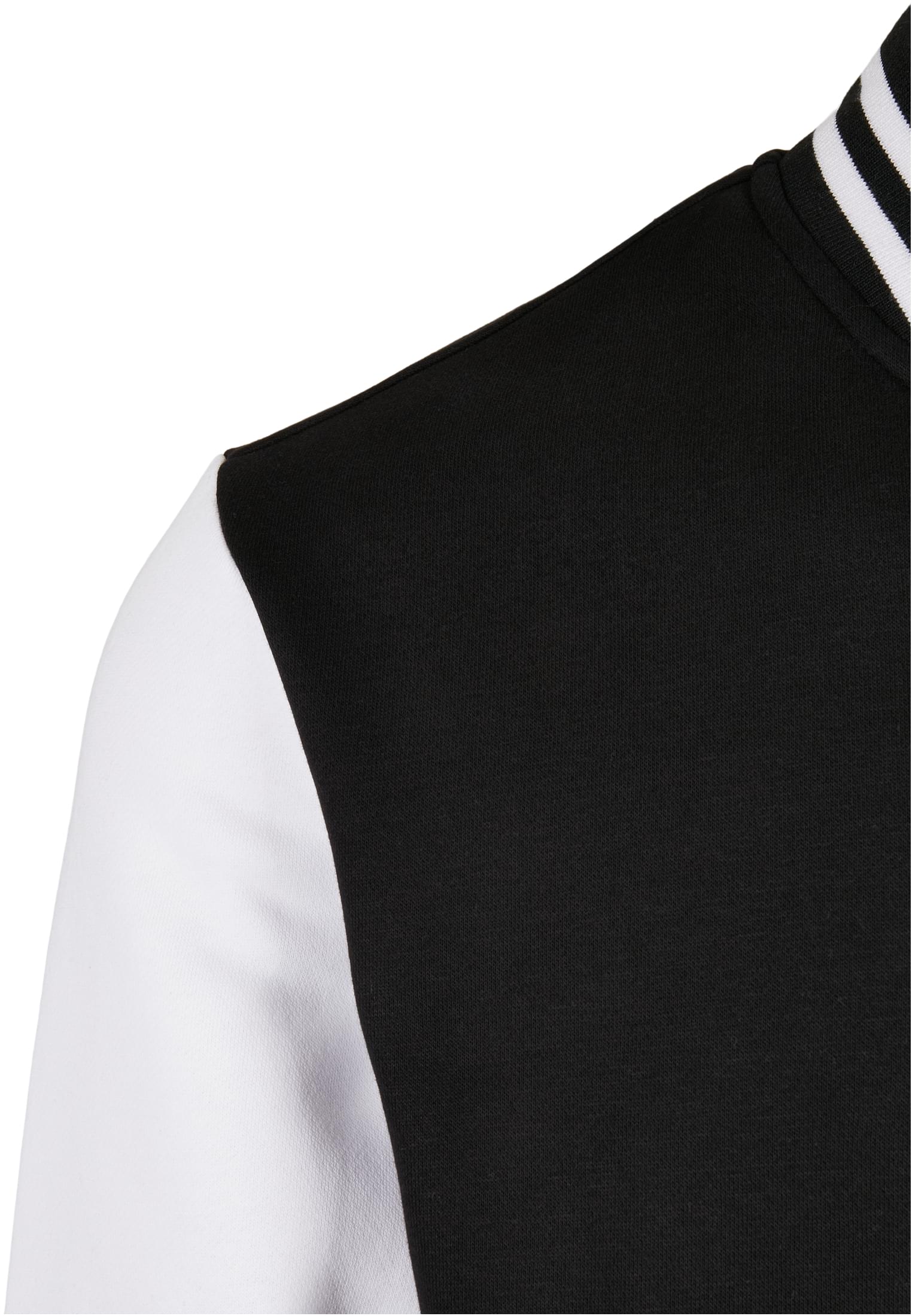 Närbild på axelpartiet av SBL Starter College Fleece Jacket, som visar den svarta kroppen, den vita ärmen och den svart- och vitrandiga kragen.