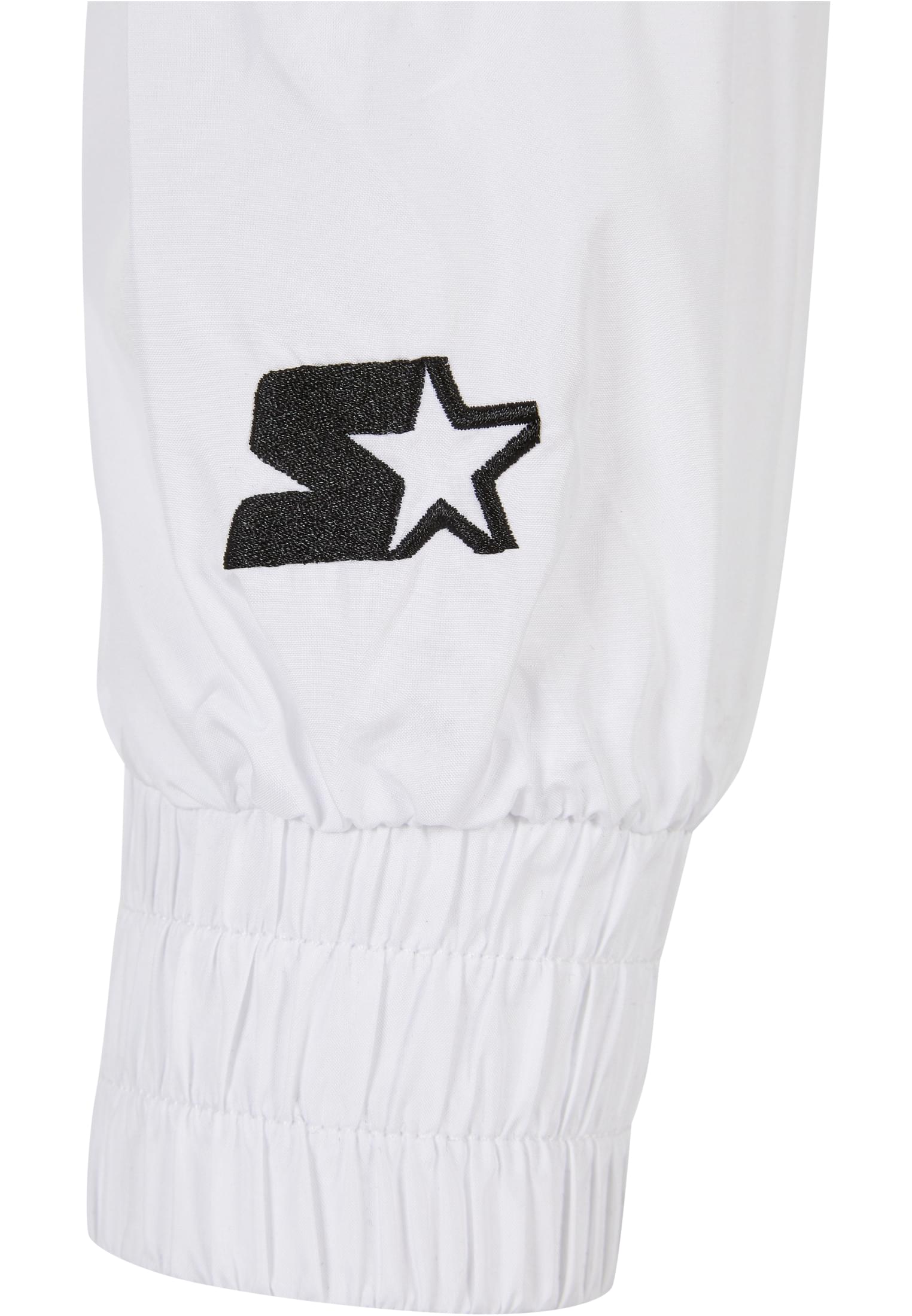 Närbild på den svarta, broderade Starter-logotypen och den elastiska mudden på ärmen till en vit SBL Starter Colorblock Pull Over Jacket.