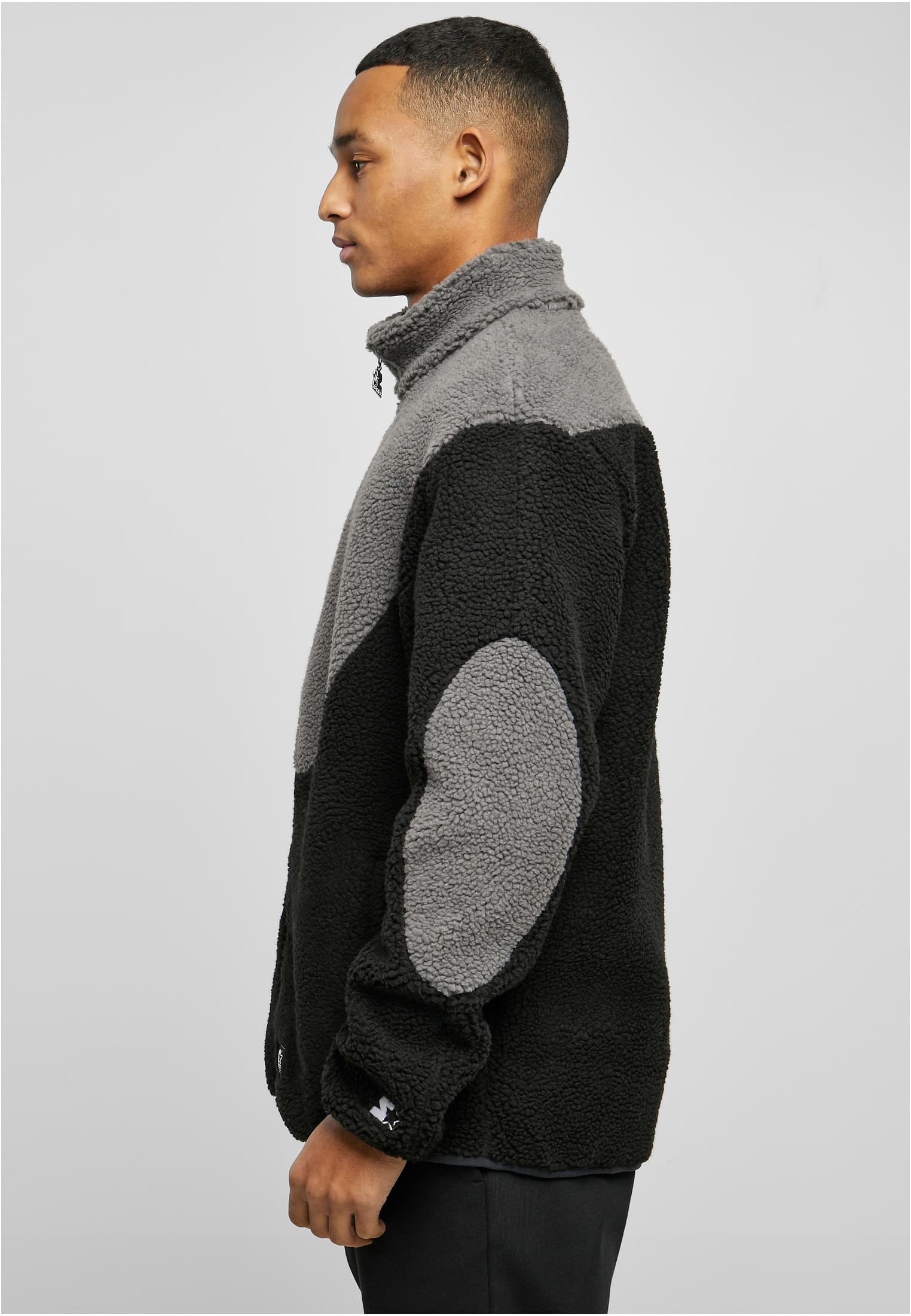 En man visar sidoprofilen av en svart och grå SBL Starter Sherpa Fleece Jacka.