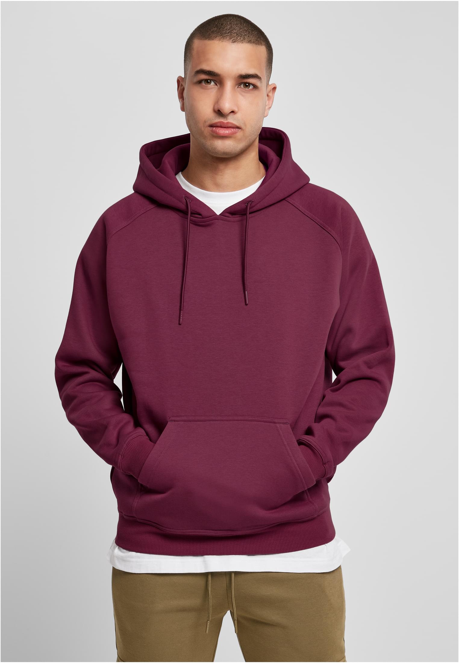 En man poserar framifrån i en vinröd UC Blank Hoody med händerna i kängurufickan.