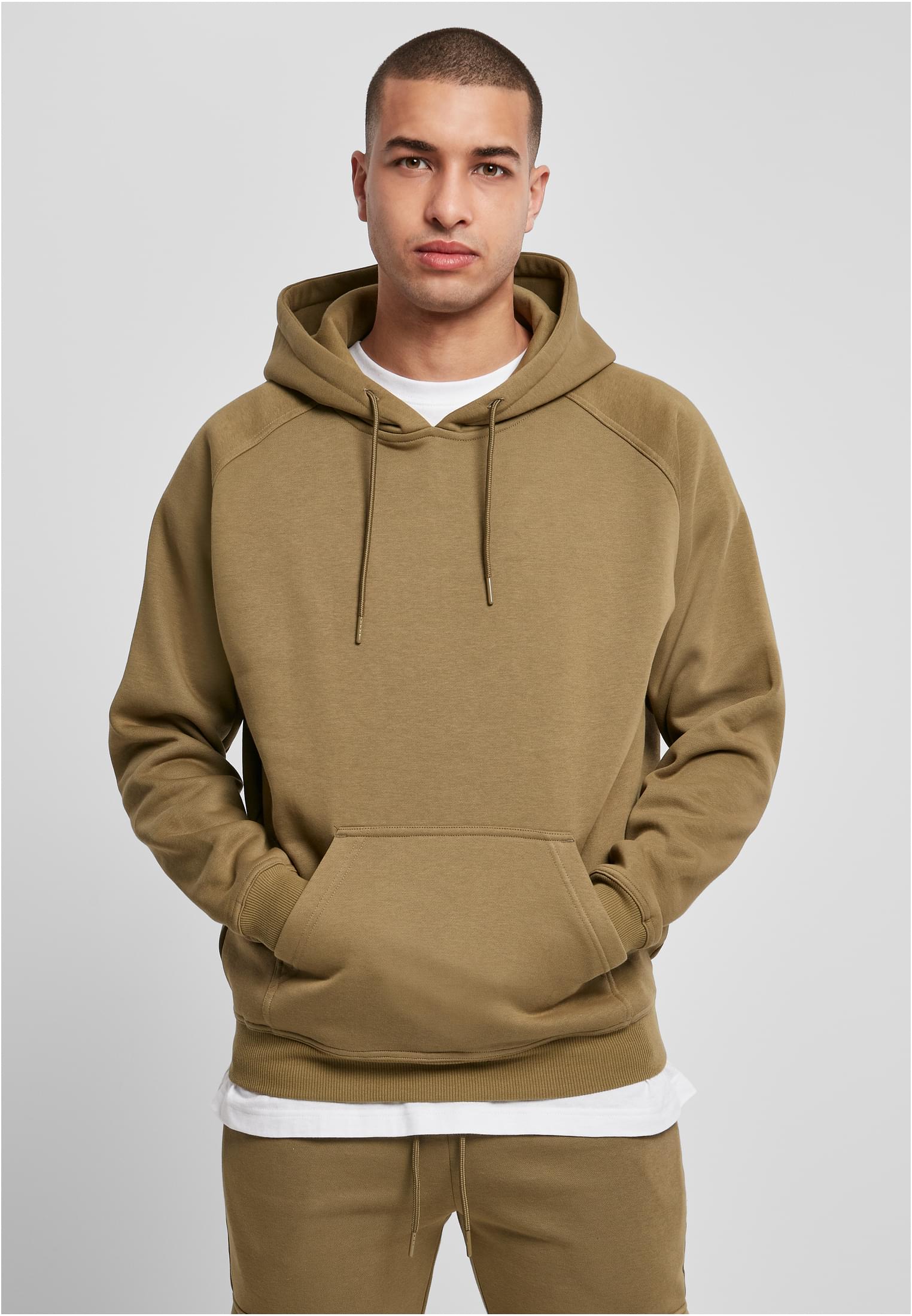 En manlig modell som bär en ljusgrön UC Blank Hoody. Han står vänd framåt med händerna i kängurufickan.