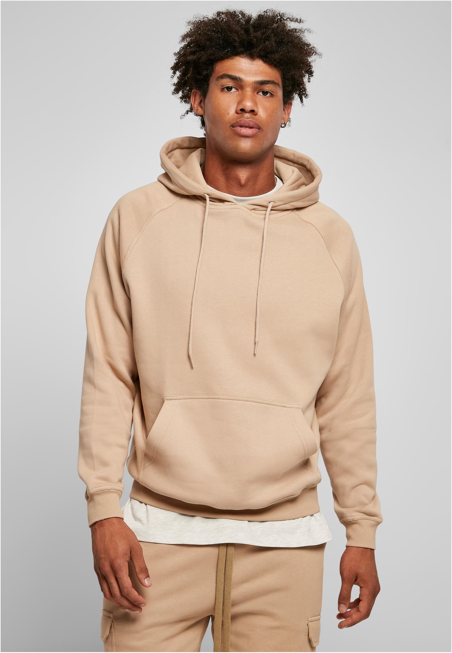 Manlig modell visar framsidan av den beigefärgade UC Blank Hoody.