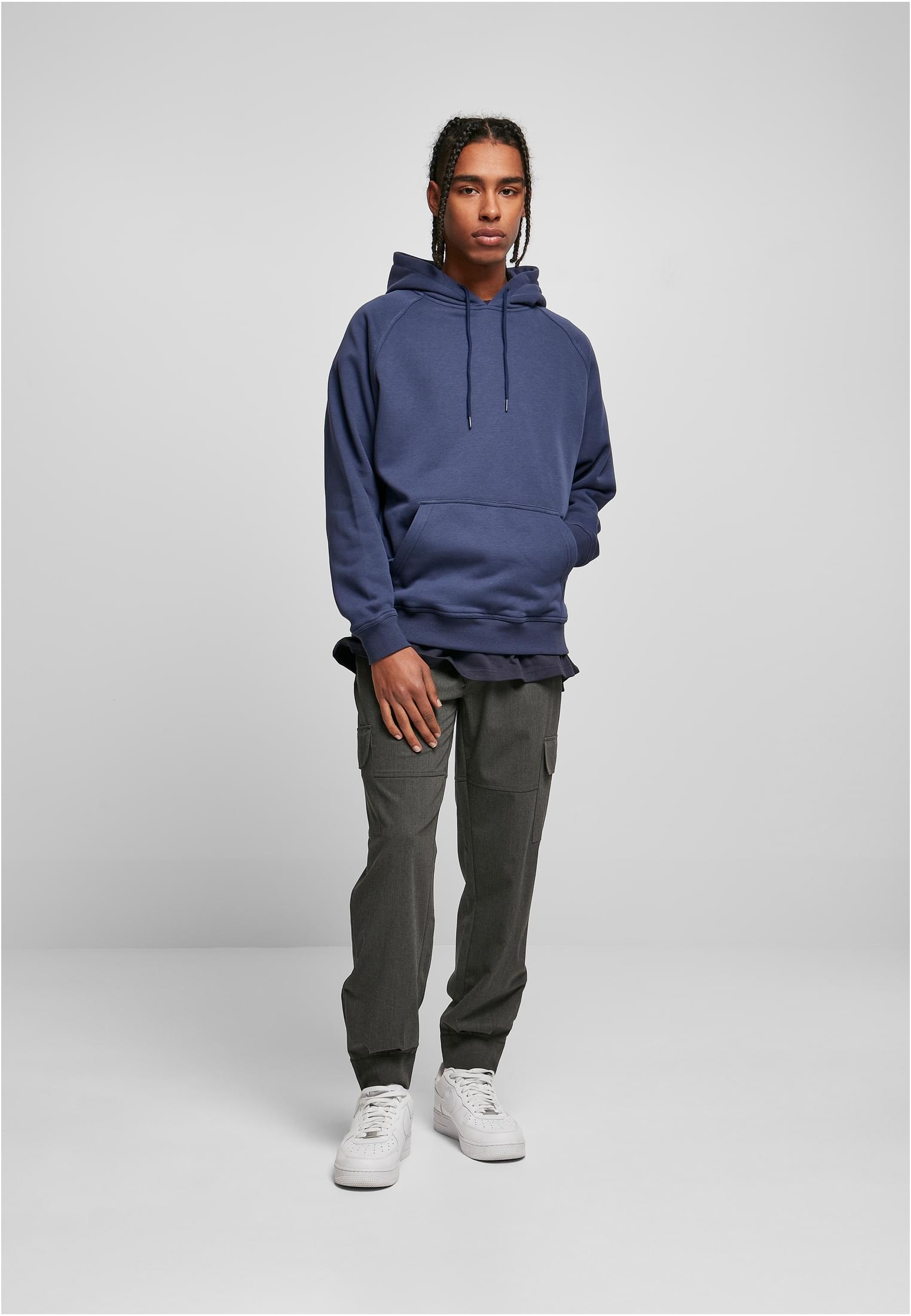 Manlig modell klädd i en mörkblå UC Blank Hoody, mörkgrå cargobyxor och vita sneakers.