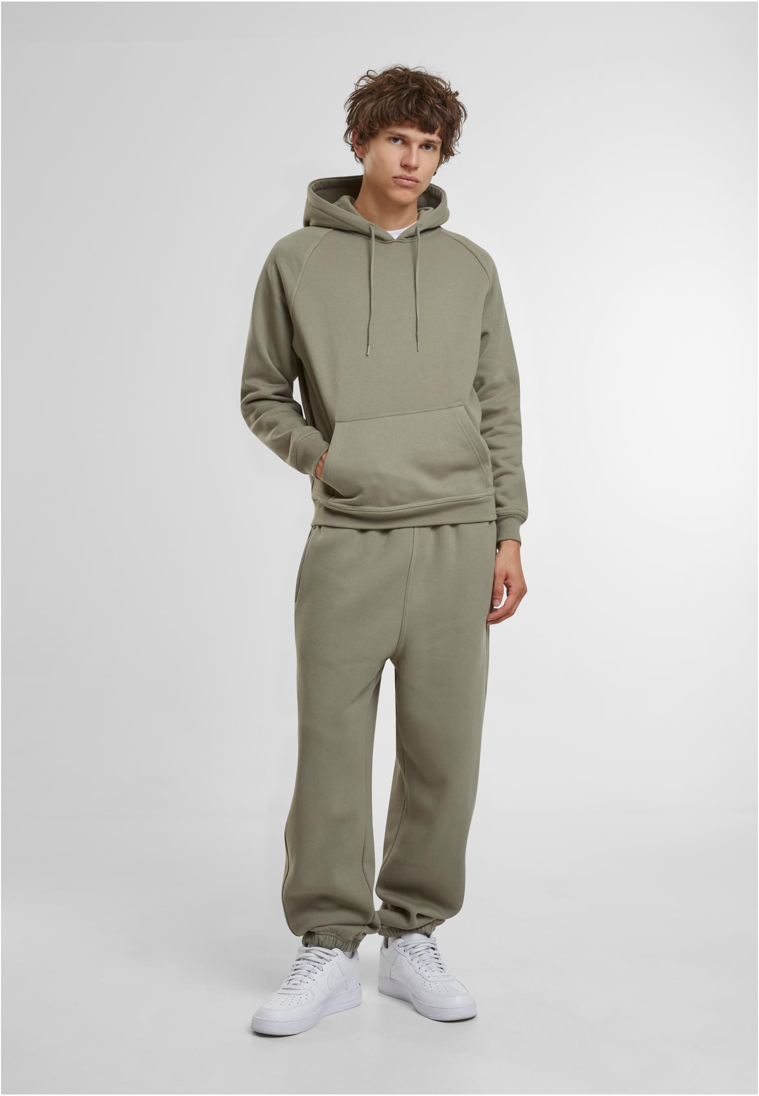 En manlig modell som bär en ljusgrön huvtröja och matchande mjukisbyxor mot en vit bakgrund.