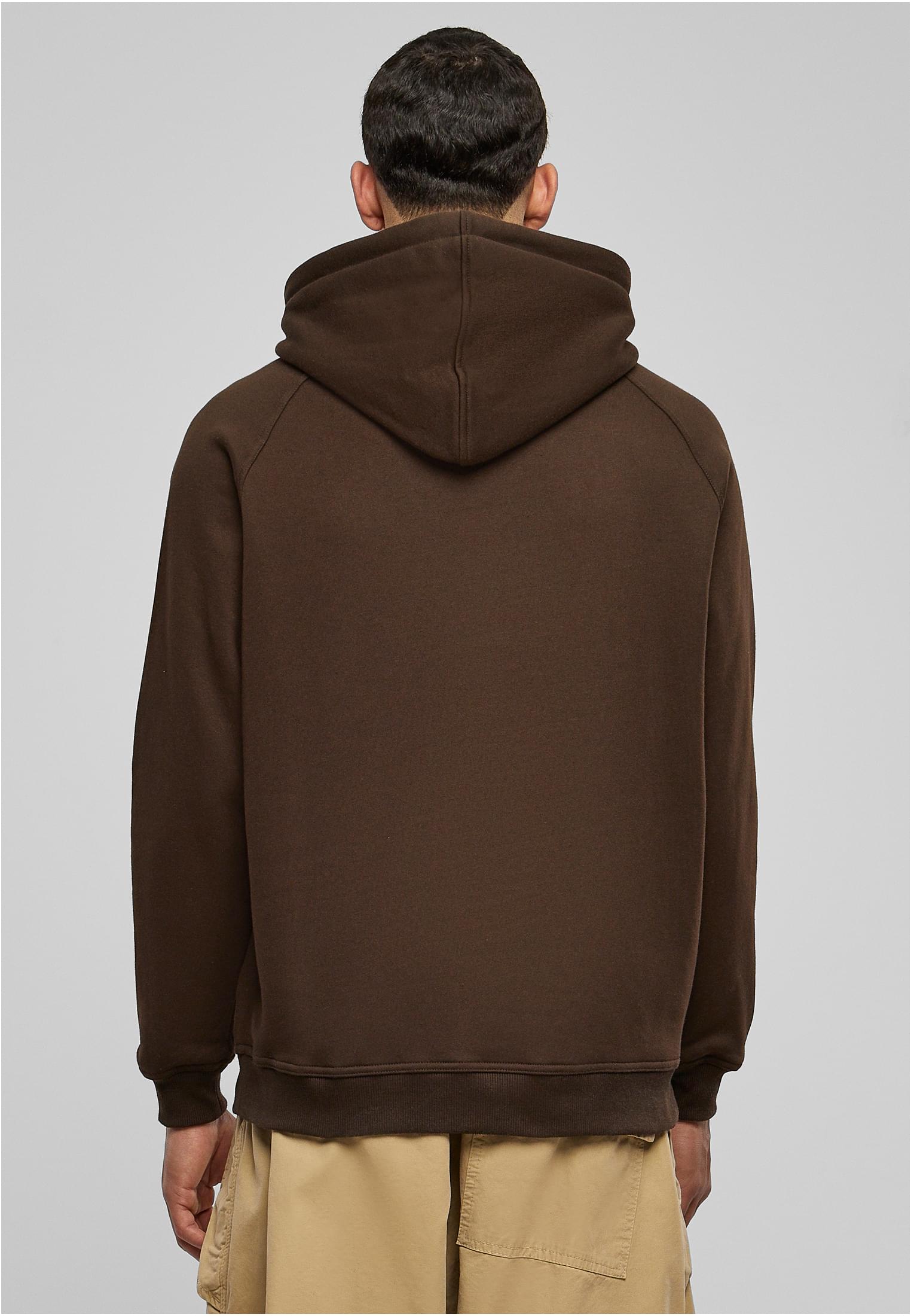 En man sedd bakifrån, klädd i en brun hoodie och beiga byxor.