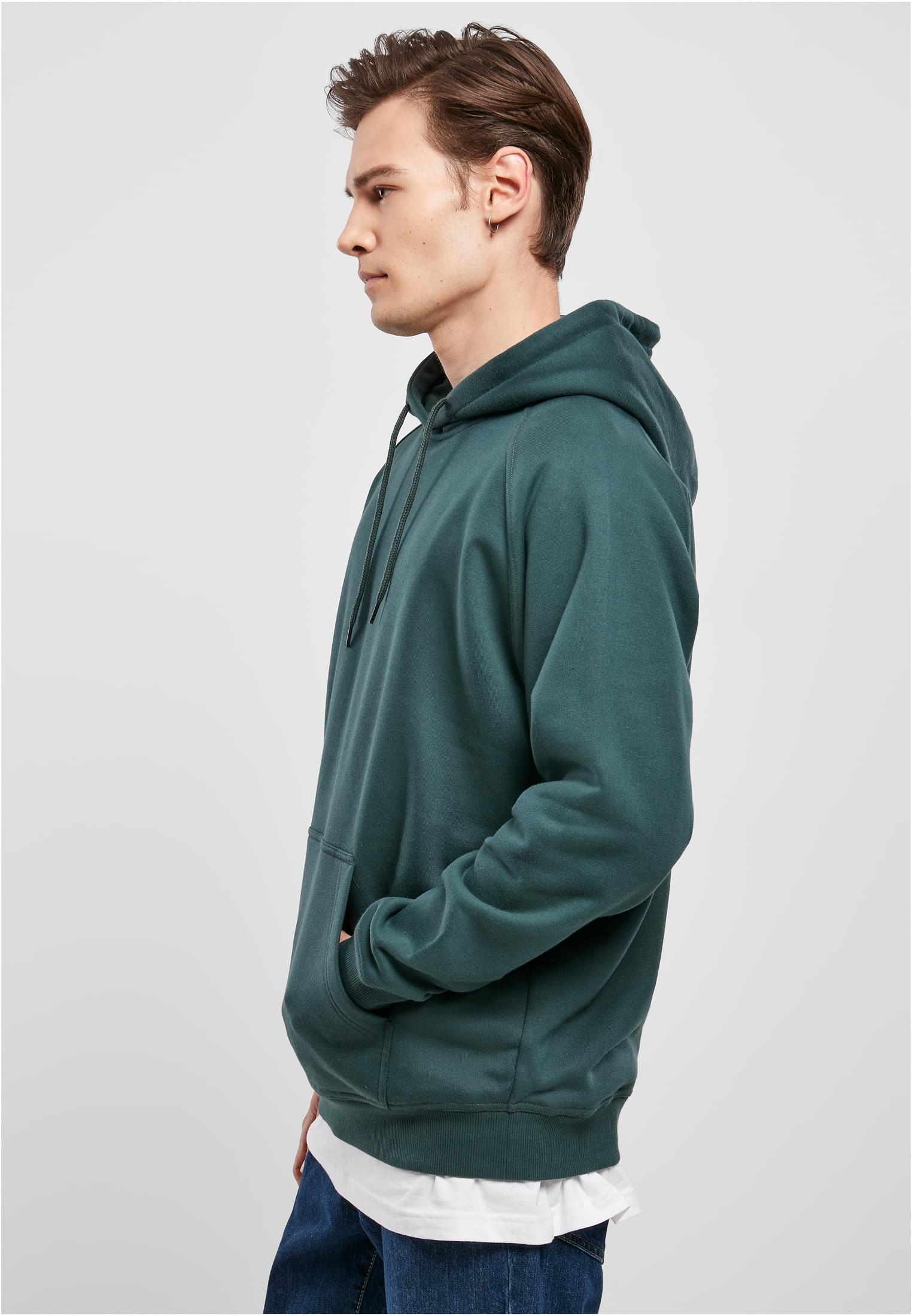 Man i profil som bär en grön UC Blank Hoody luvtröja.
