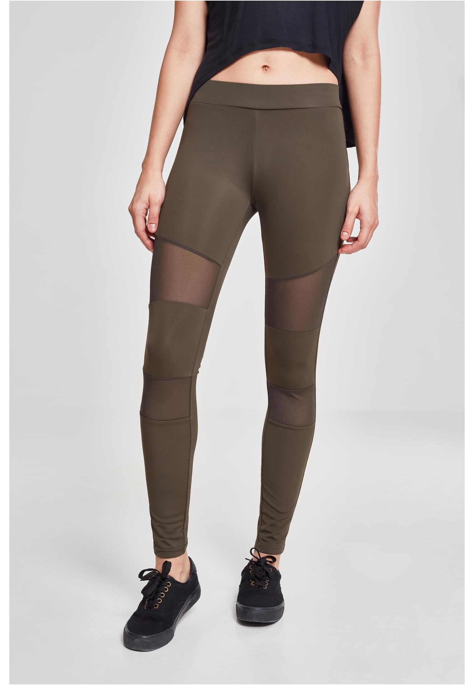 Kvinna som bär varmgrå Tech Mesh Leggings med transparenta nätinsatser.
