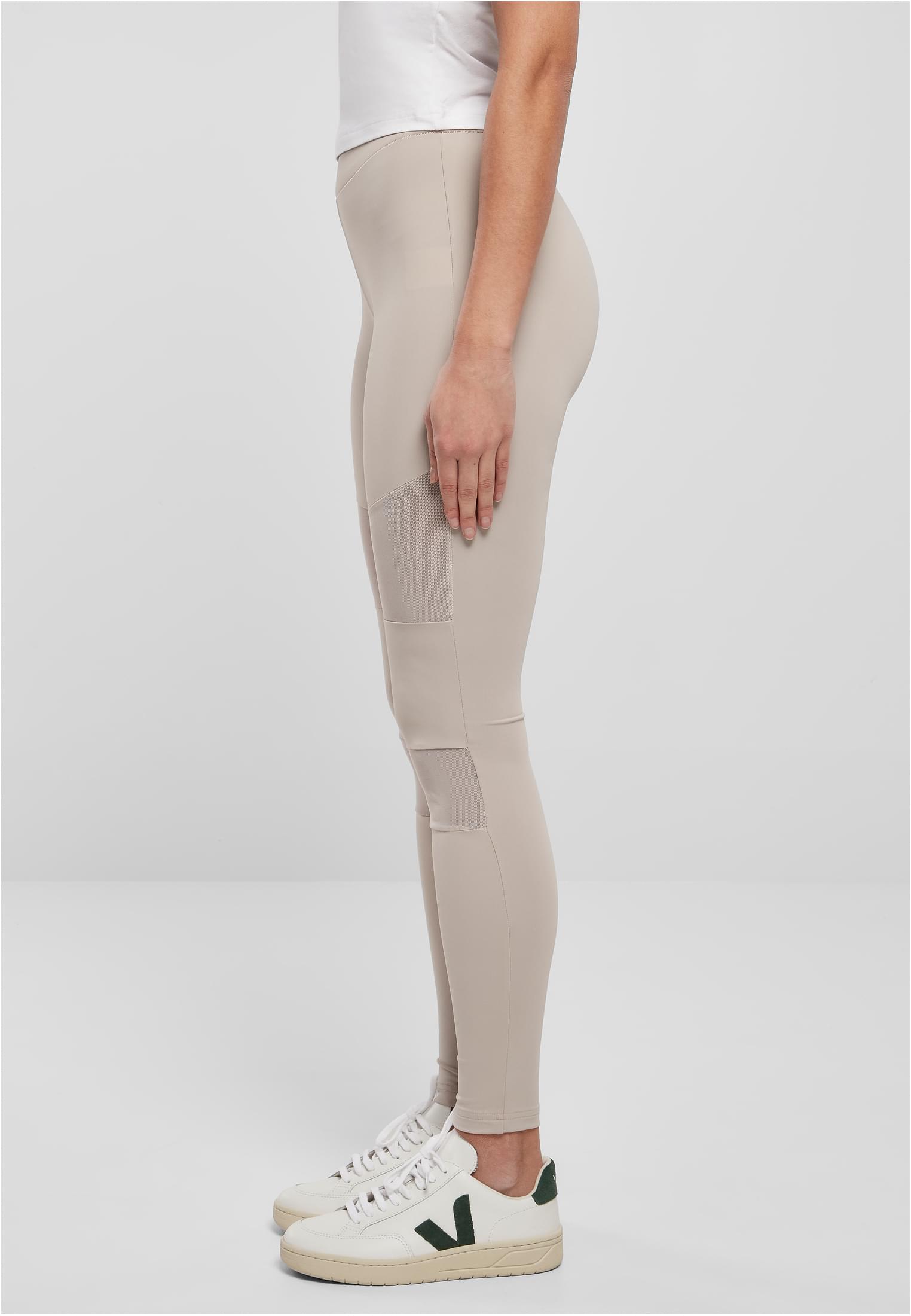 Sidovy av en modell som bär ljusgråa UC Ladies Tech Mesh Leggings med nätpaneler på lår och knän.