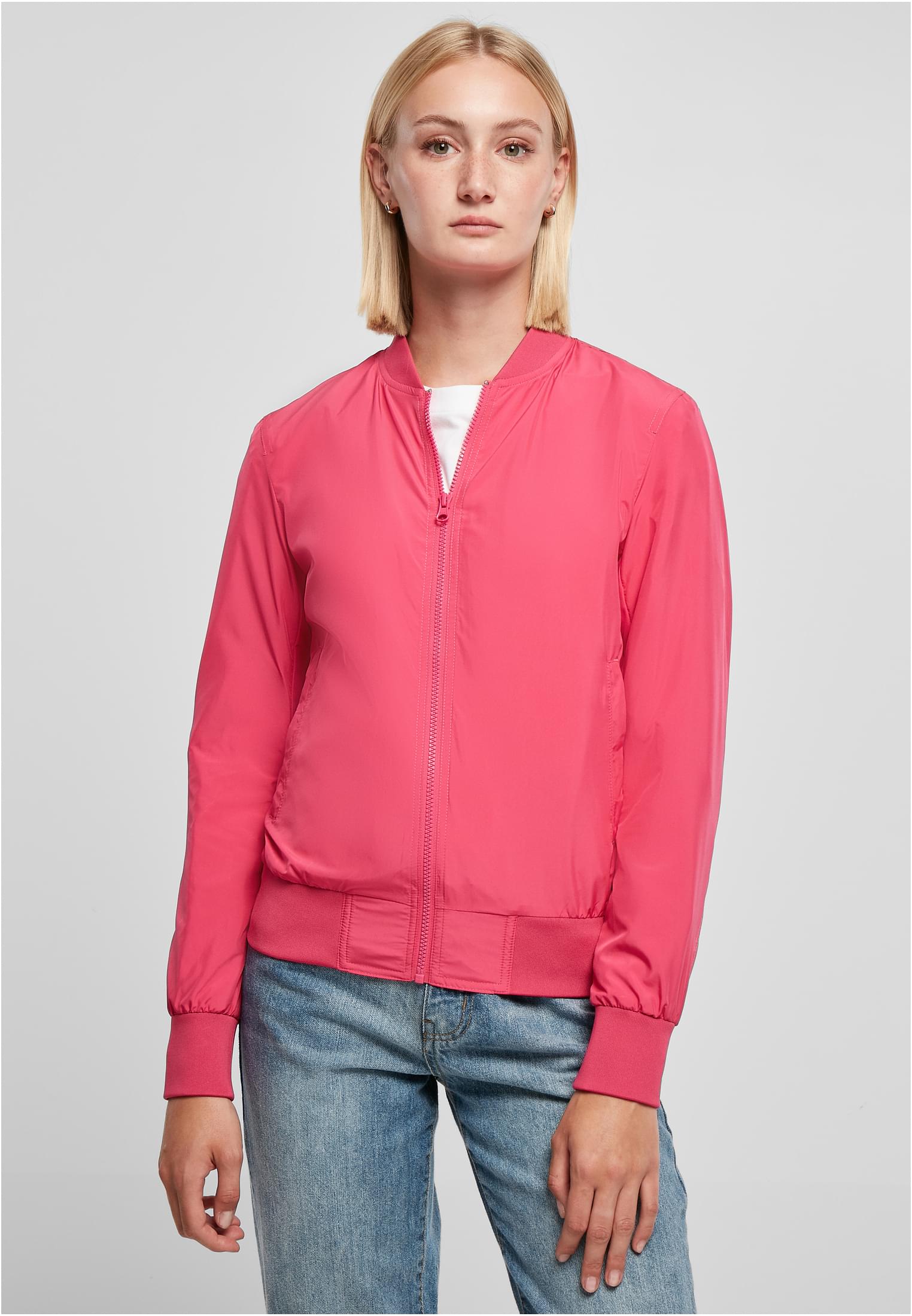 En kvinna visar framsidan av en rosa UC Light Bomber Jacket.