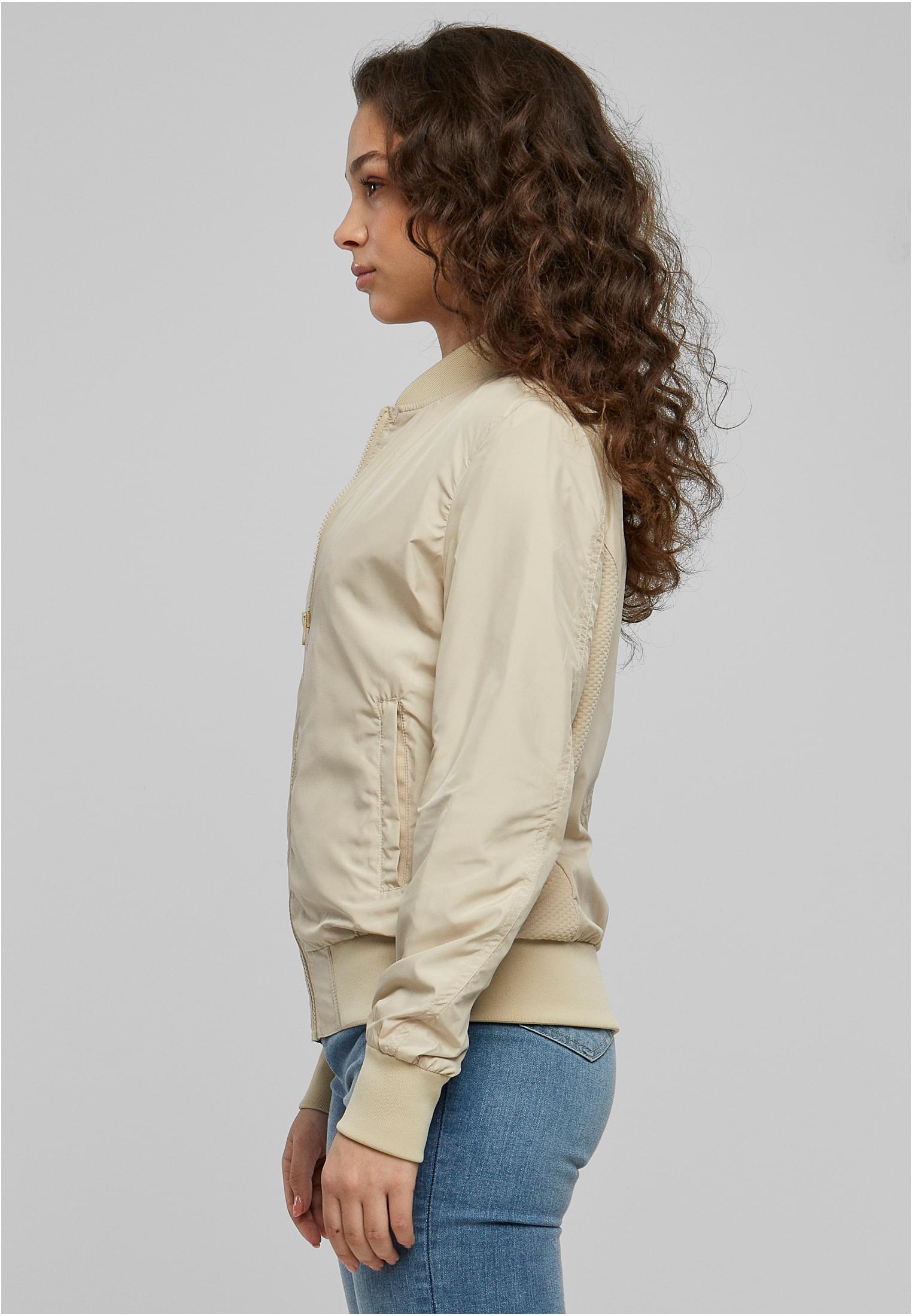 En kvinna visar sidan av en beige UC Light Bomber Jacket.