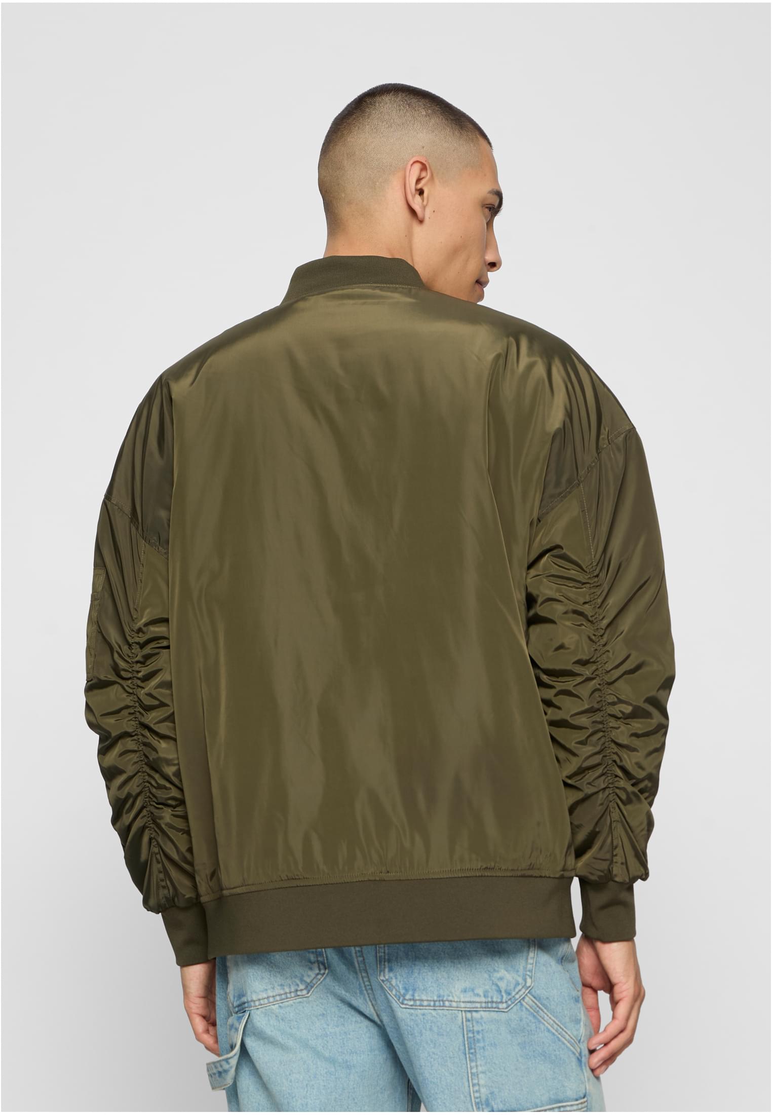 En man visar baksidan av den olivgröna UC Oversized Bomber Jacket.