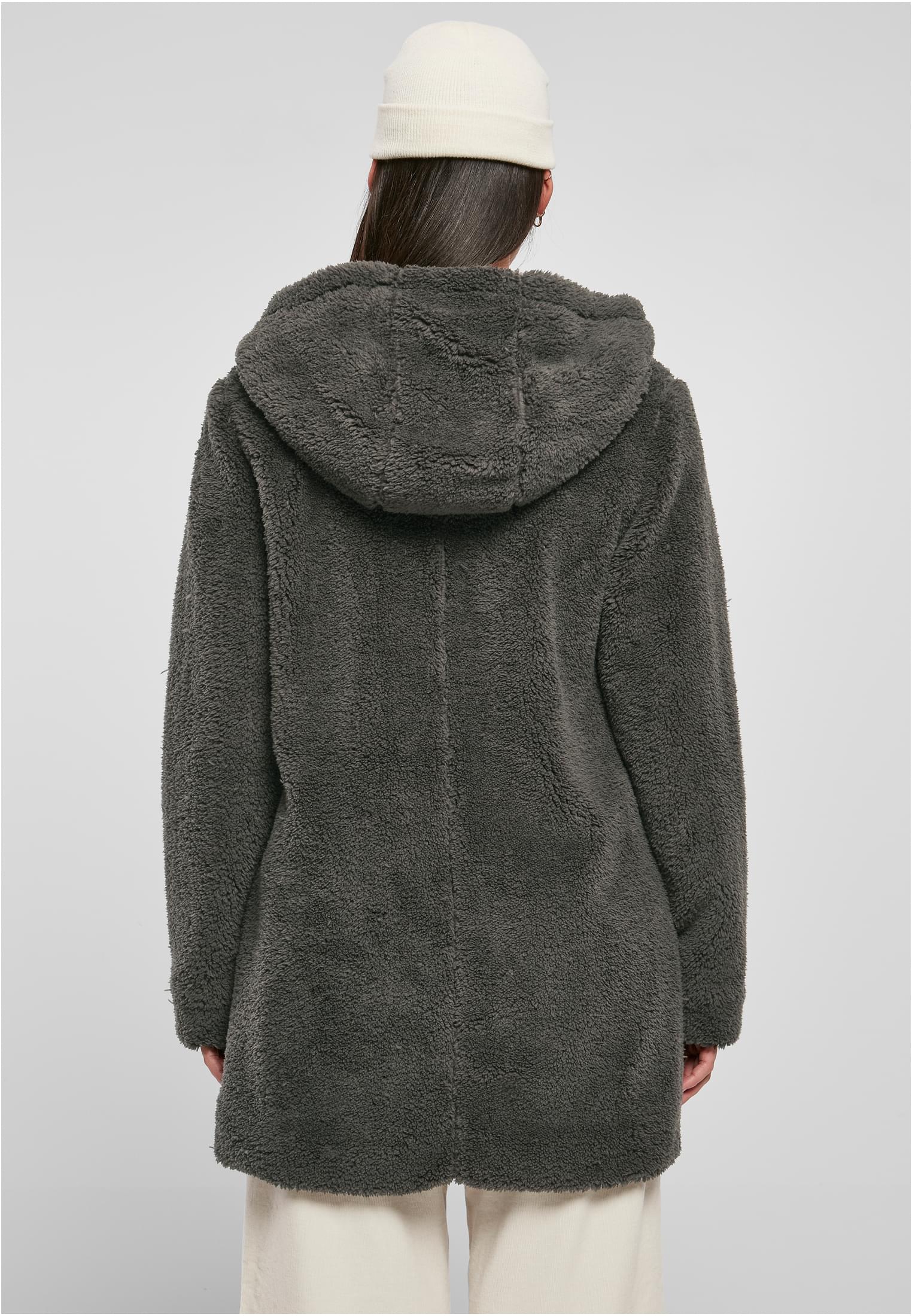 En kvinna, sedd bakifrån, som bär en mörkgrå och fluffig sherpajacka med huva.