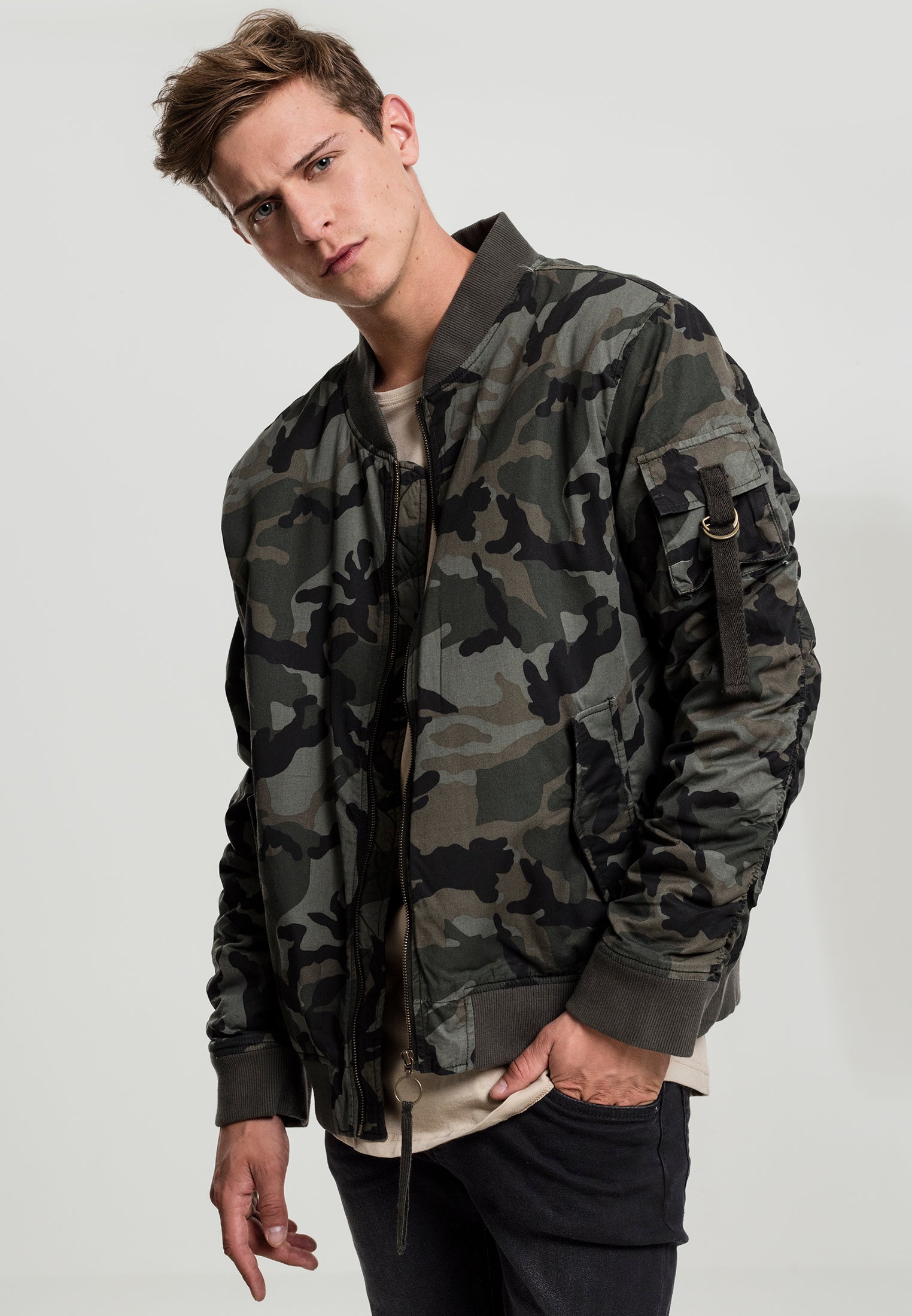 En man visar framsidan av UC Vintage Camo Cotton Bomber Jacket i grönt kamouflagemönster.