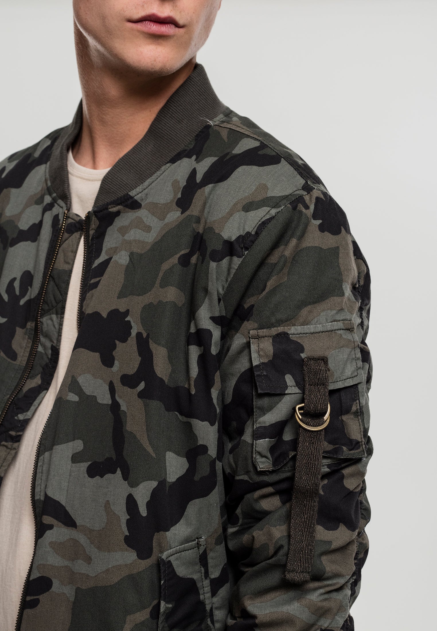 Närbild på en man som bär en UC Vintage Camo Cotton Bomber Jacket, med fokus på jackans kamouflagemönster, axelparti och fickan på ärmen.