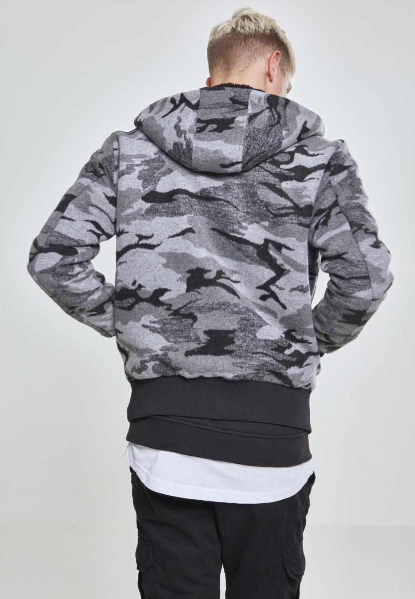 En man visar baksidan av en UC Camo Zip Jacket i grått kamouflagemönster.