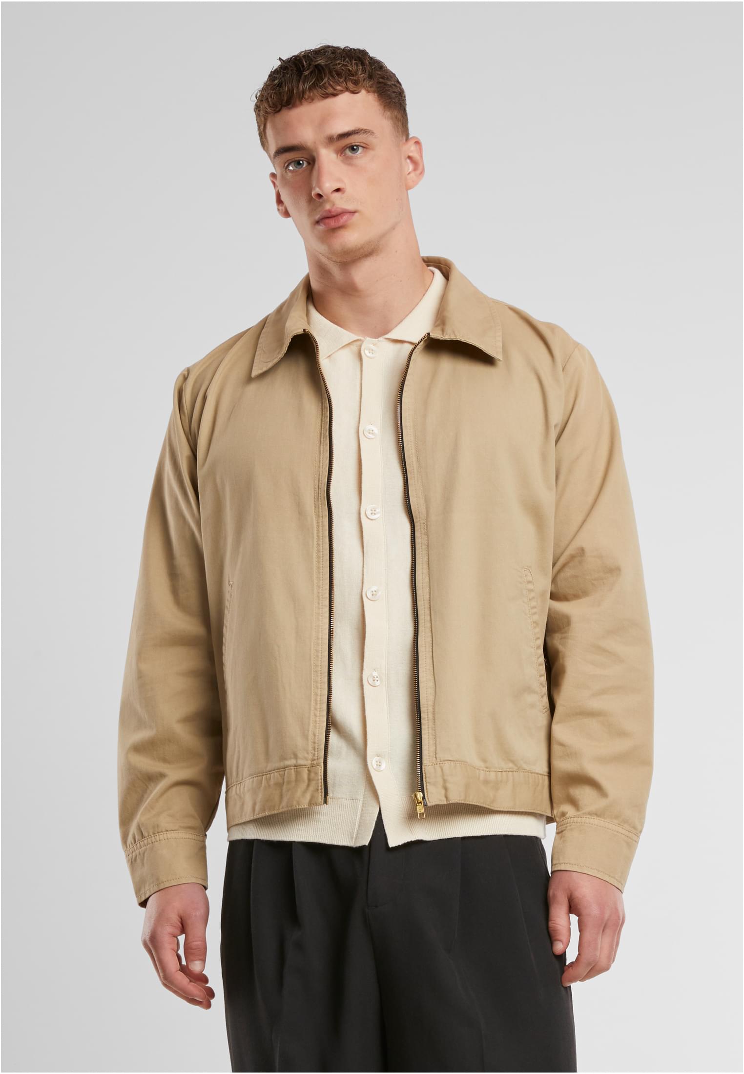En man som bär en beige UC Workwear Jacket, fotograferad framifrån mot en vit bakgrund.