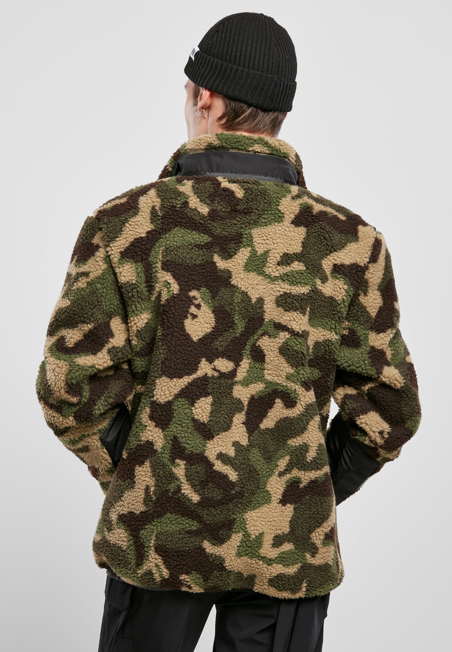 Baksidan av en man som bär en kamouflagemönstrad UC Sherpa Jacket och en svart mössa.