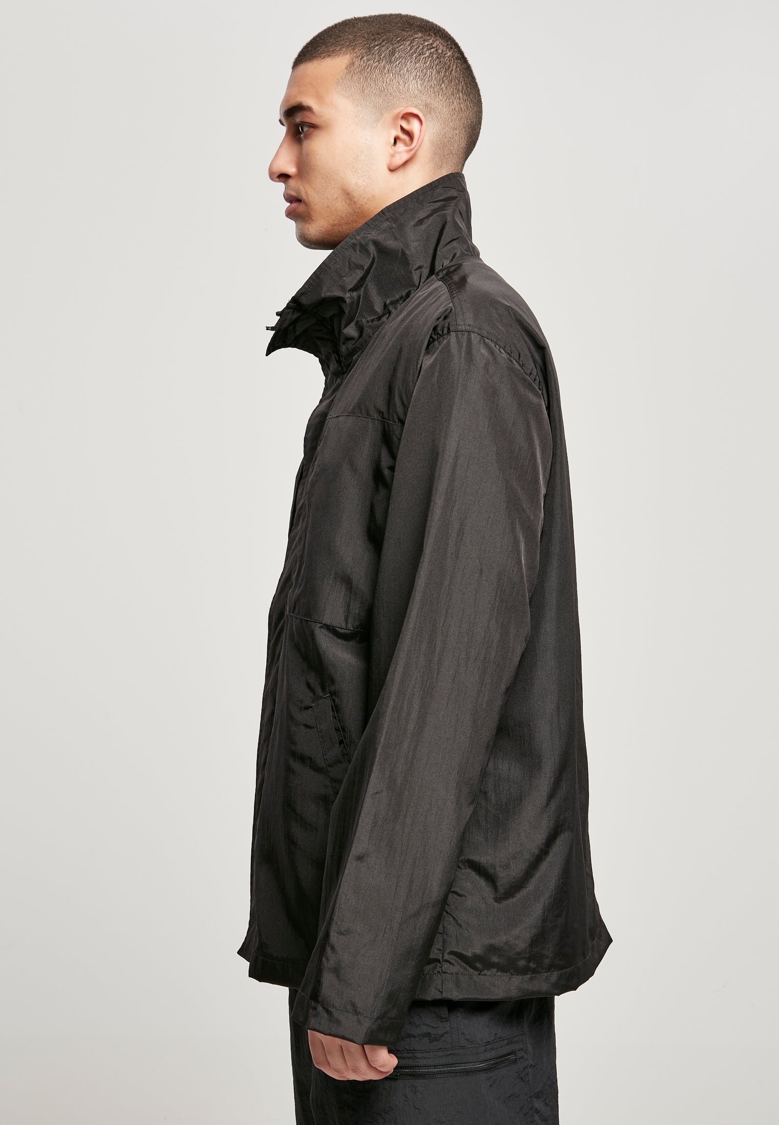 Sidovy av en man som bär den svarta nylonjackan UC Double Pocket Nylon Crepe Jacket.