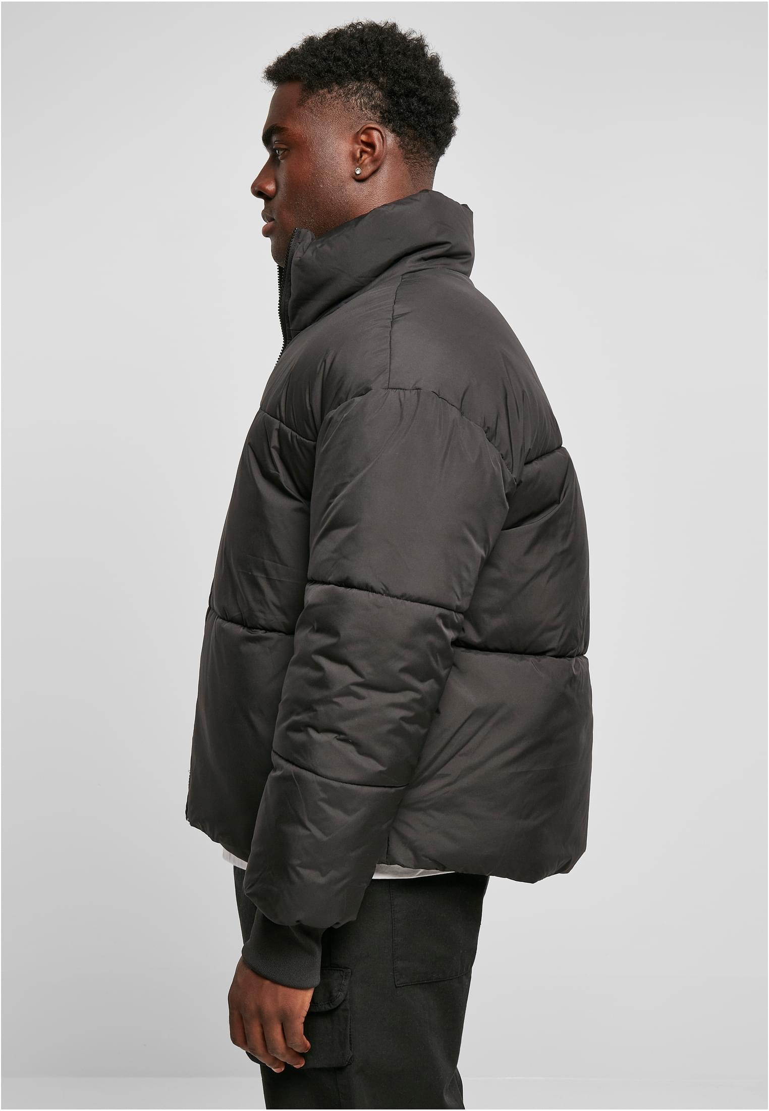 En man i profil som bär den svarta UC Short Big Puffer Jacket.