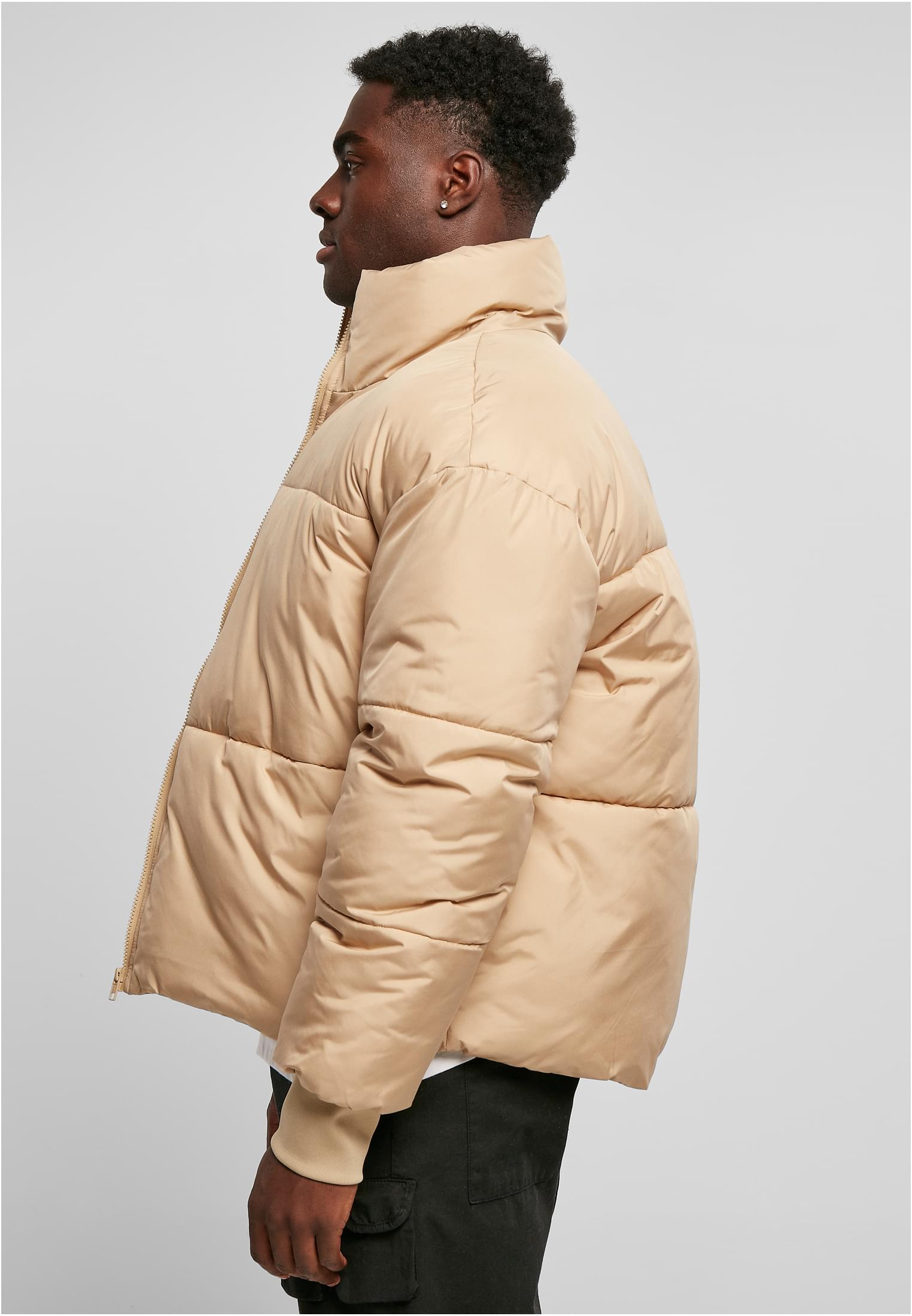 Sidovy av en man som bär en beige UC Short Big Puffer Jacket.