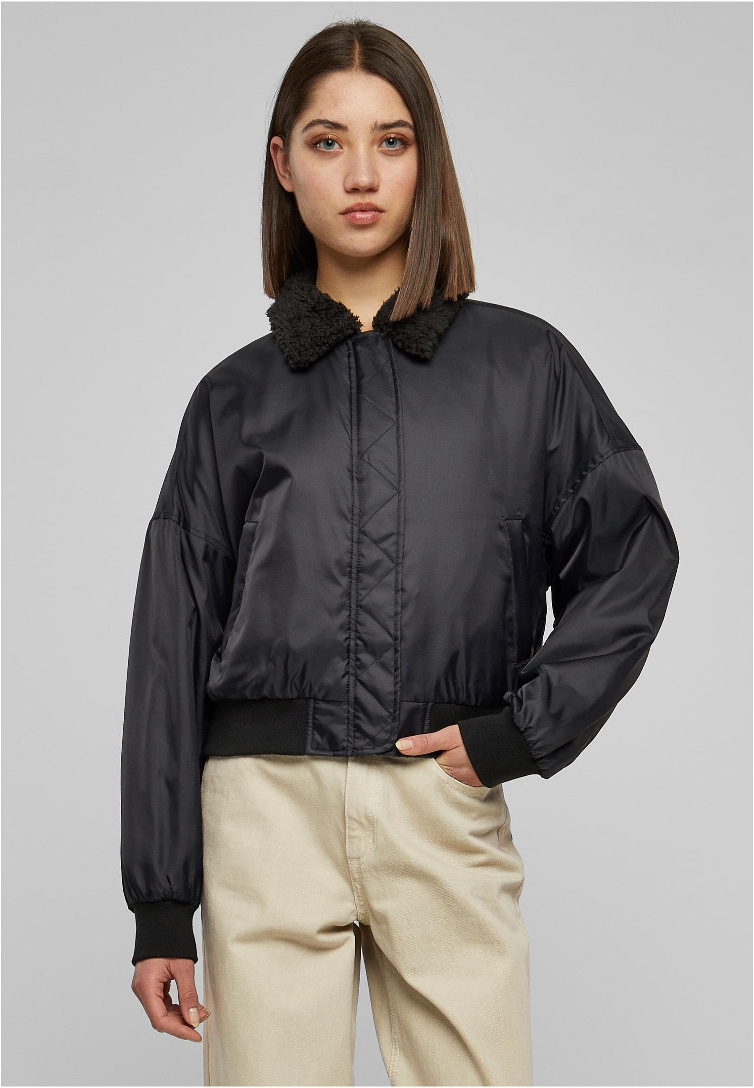 En kvinna visar framsidan av den svarta UC Pilot Bomber Jacket med sherpakrage.
