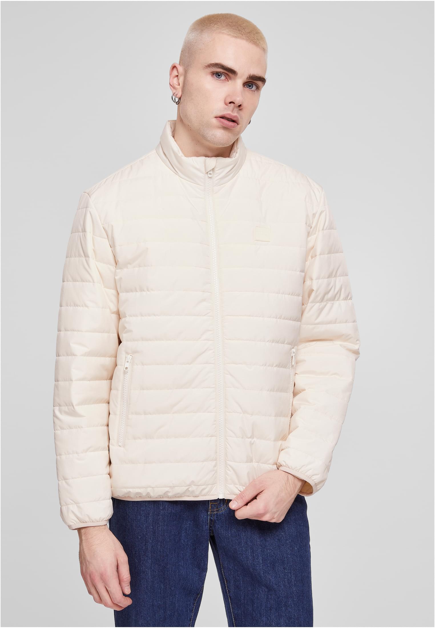 En man med blont hår bär en beige UC Light Bubble Jacket och blåjeans.