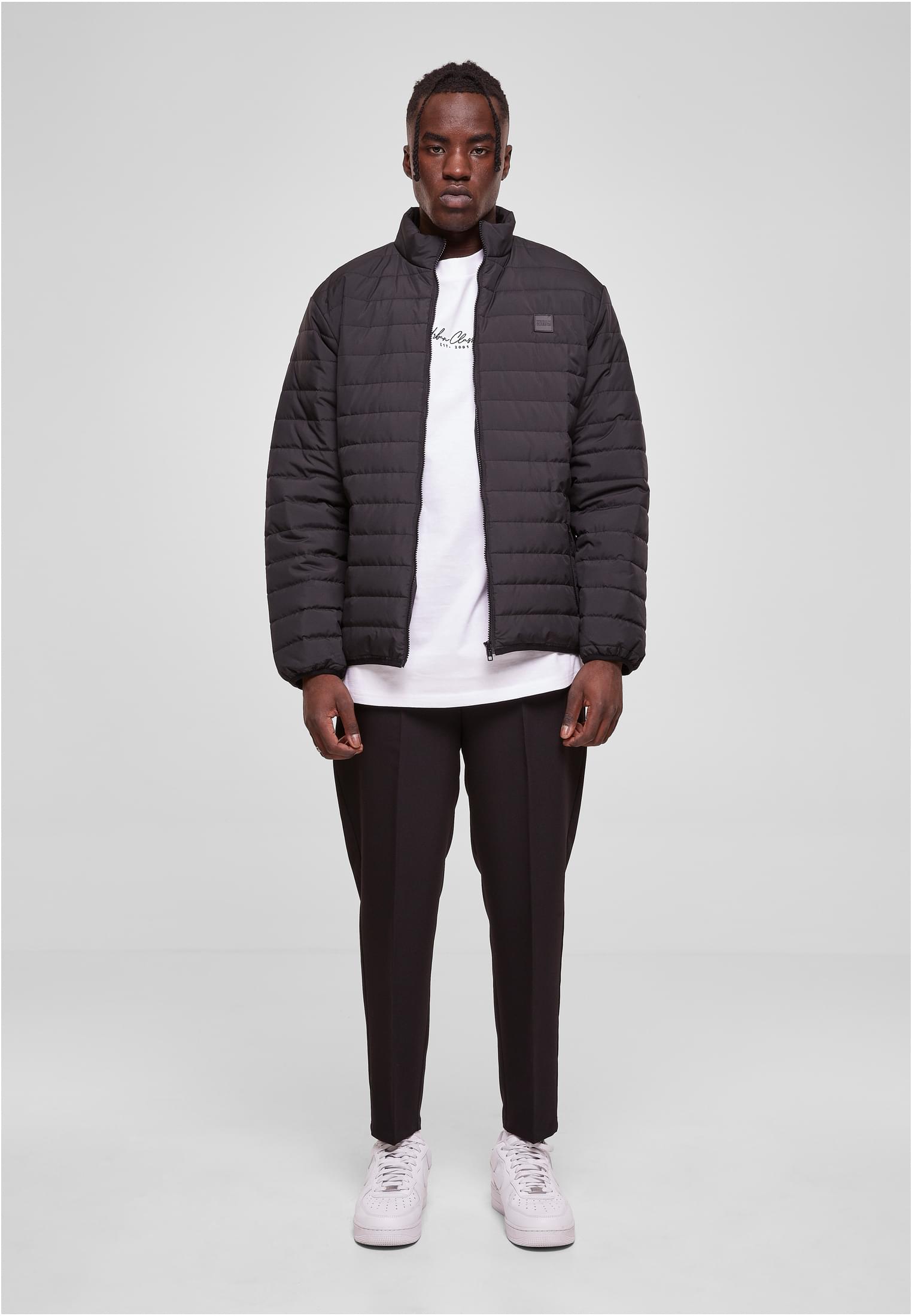 En man visar framsidan av den svarta quiltade jackan UC Light Bubble Jacket.