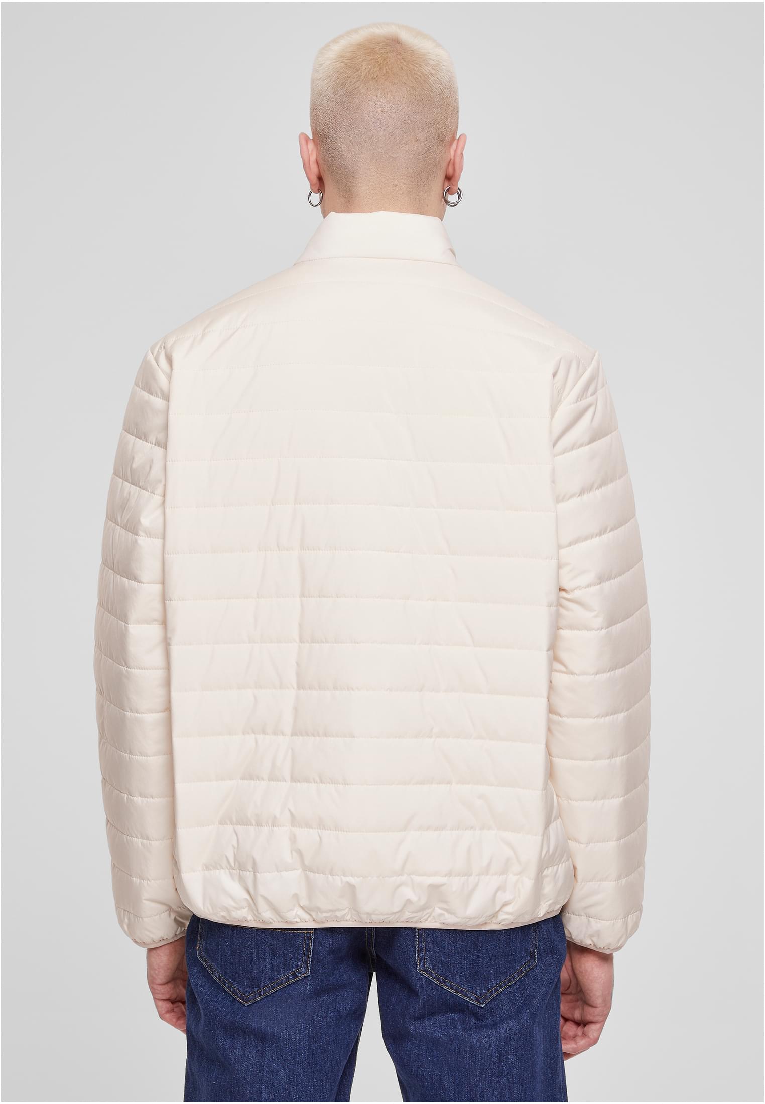 En man visar baksidan av en beige UC Light Bubble Jacket.