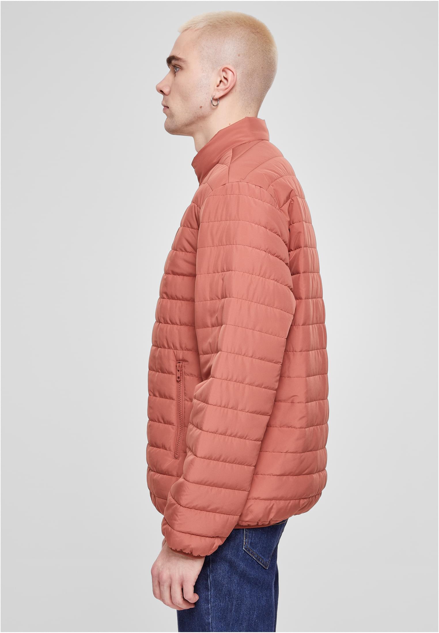 En man i profil som bär den orangea UC Light Bubble Jacket.
